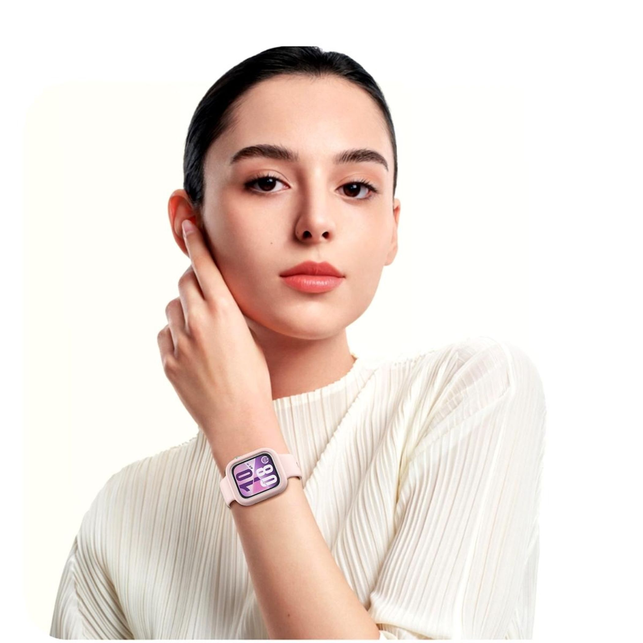 Una donna con smartwatch rosa, si tocca l'orecchio. Sfondo bianco e abiti chiari.