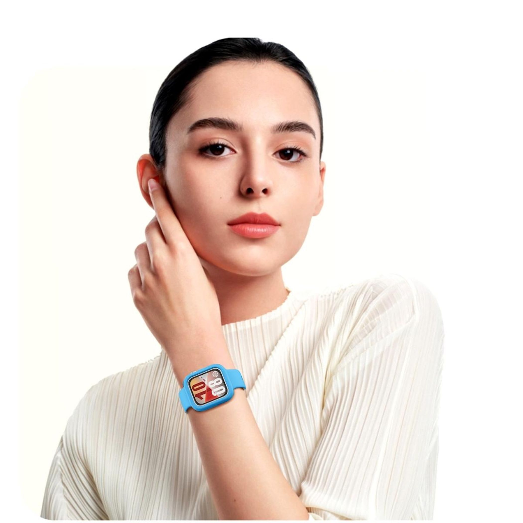 Una donna con camicia bianca e smartwatch blu. Si tocca l'orecchio con una mano.