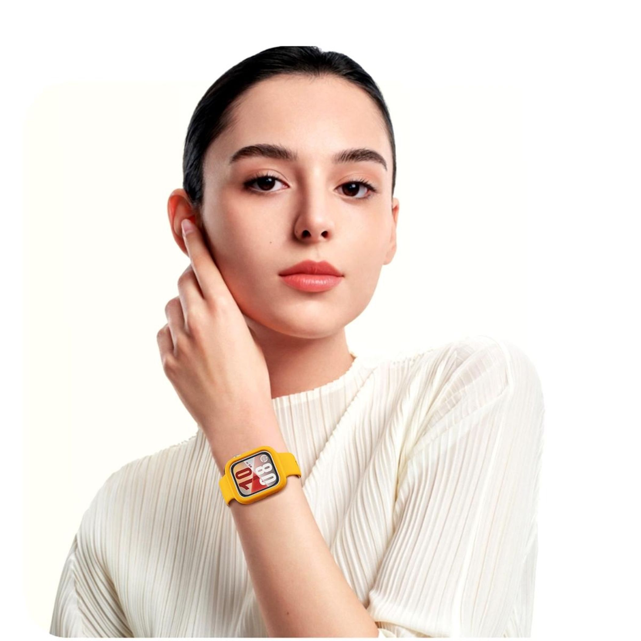 Una donna con un orologio giallo. Si tocca l'orecchio con una mano. Sfondo bianco.