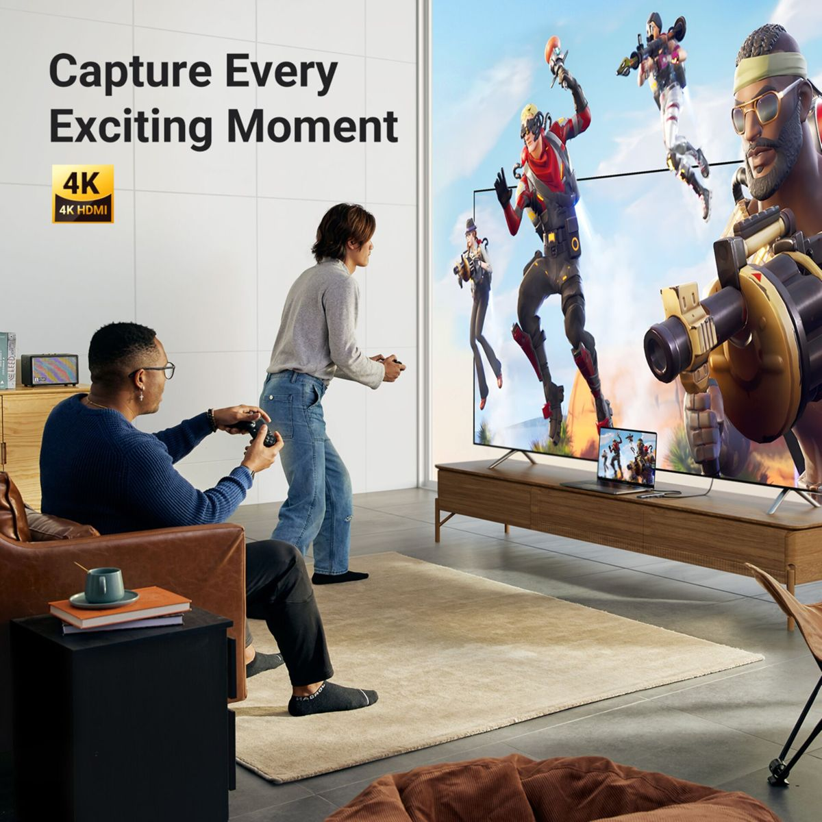 Zwei Personen spielen Videospiele in einem Wohnzimmer. Ein großer Fernseher zeigt Spielfiguren. Oben links befindet sich ein 4K HDMI-Logo.