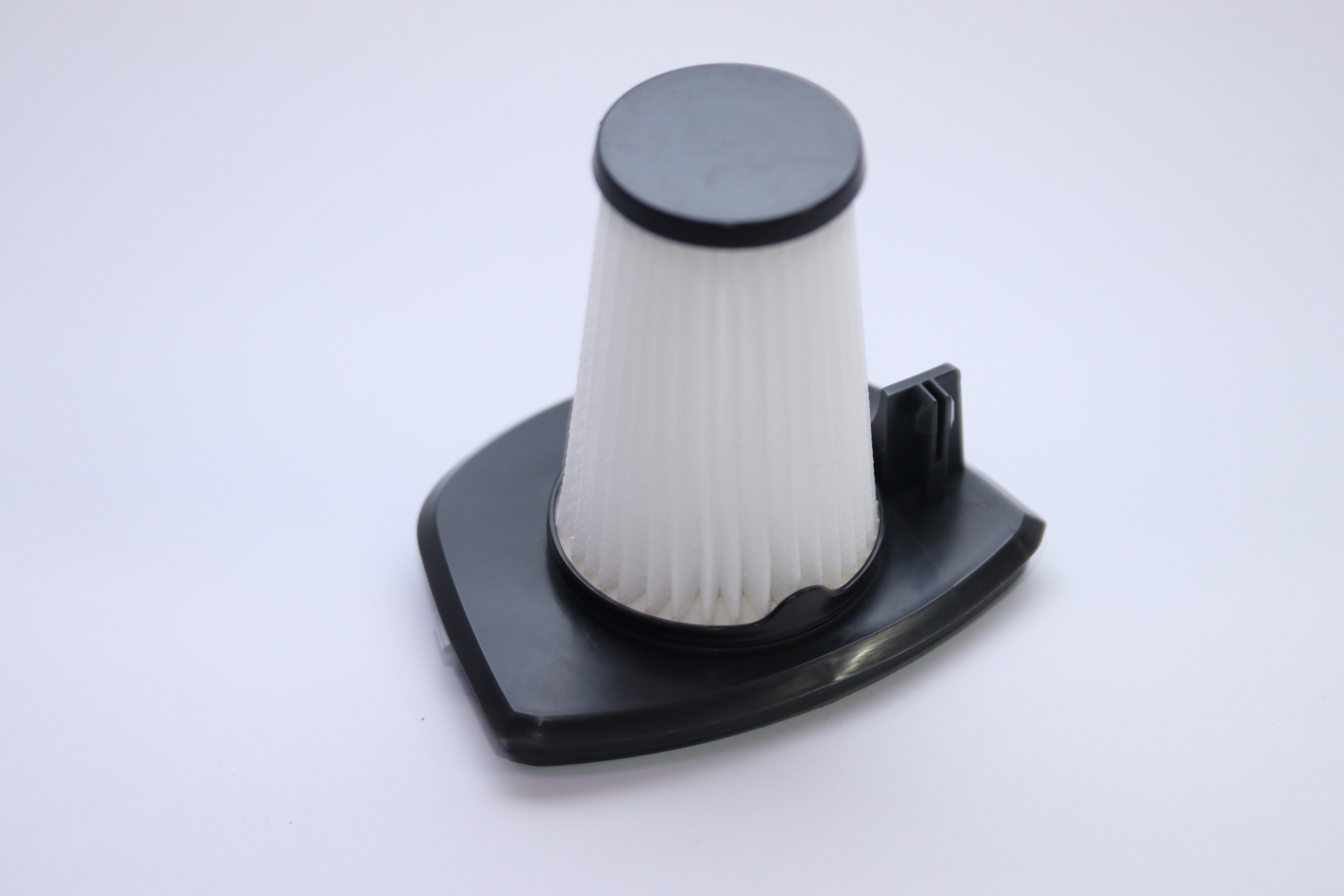 Ein Staubsaugerfilter. Er hat eine schwarze Basis und Oberseite sowie einen weißen, plissierten Filter dazwischen. Der Hintergrund ist weiß.
