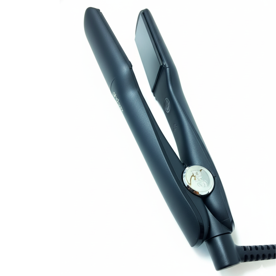 Una plancha de pelo negra sobre fondo blanco. Está abierta, mostrando las placas calefactoras. Un cable de alimentación está conectado.