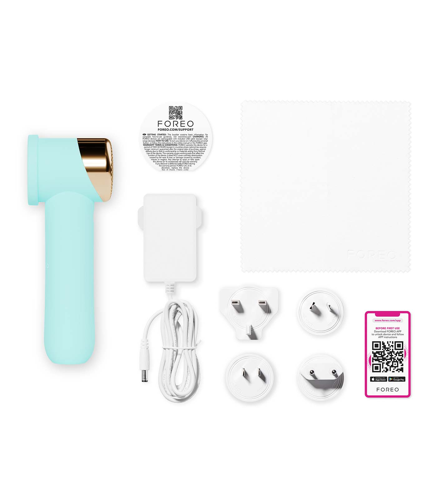 A mint and gold Foreo device, charging accessories, cleaning cloth, and a card with QR codes are on a white surface.