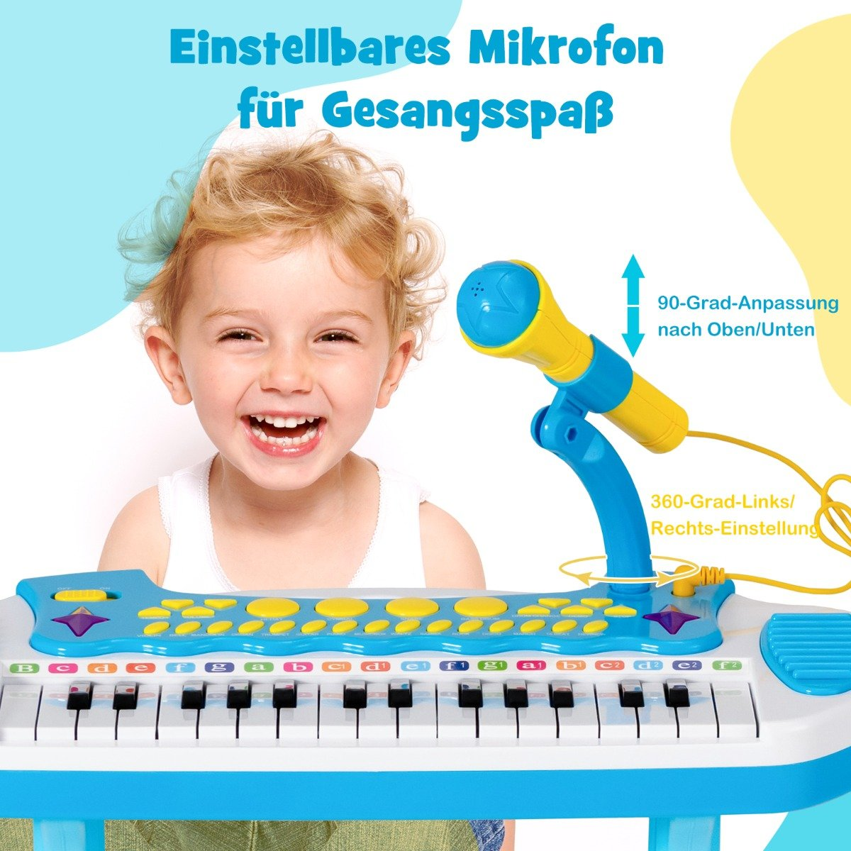 Un niño sonriente con un piano y micrófono de juguete. El piano es azul y blanco, y el micrófono es amarillo y azul.