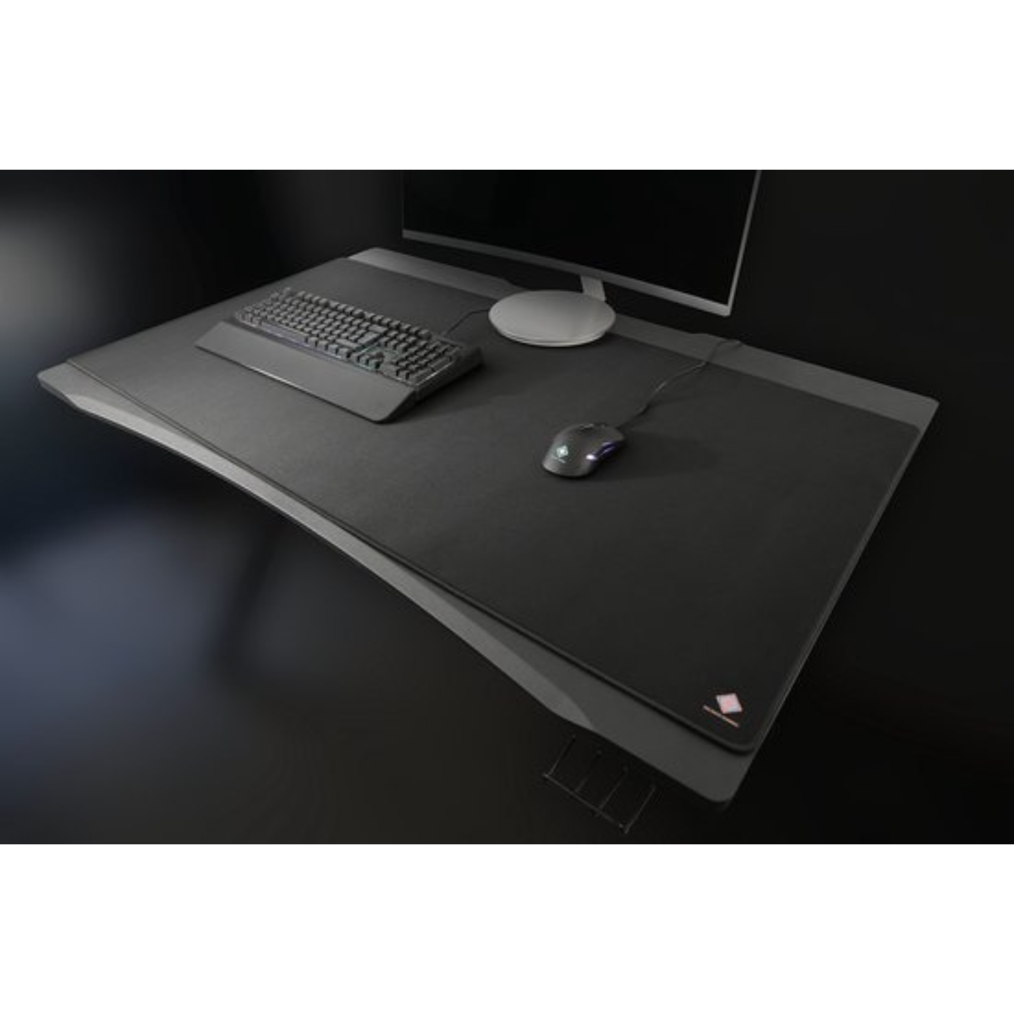 Czarny zestaw biurkowy z monitorem, klawiaturą, myszą i dużą podkładką. Ciemne tło, minimalistyczne.