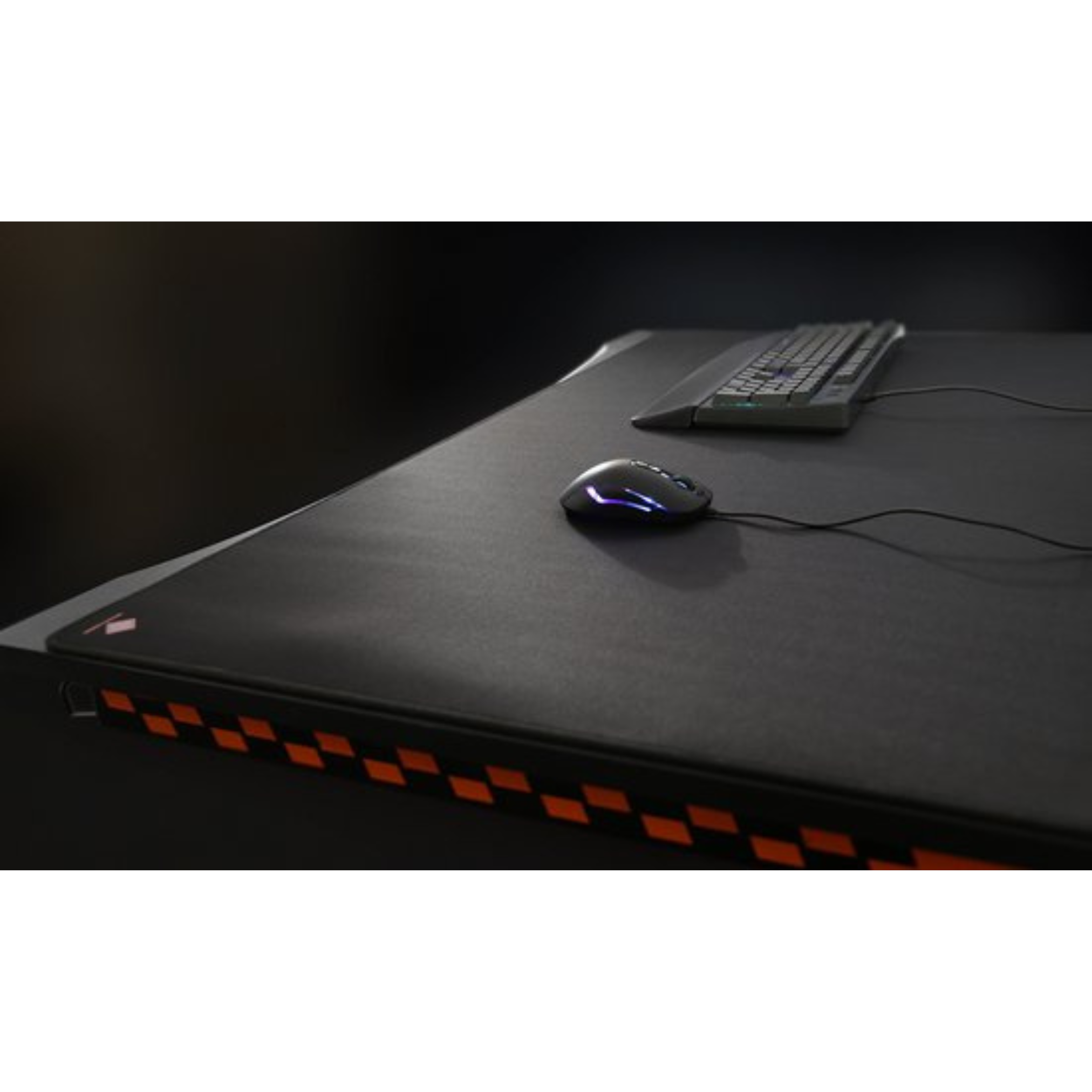 Konfiguracja biurka z klawiaturą, myszką i podkładką. Mysz ma niebieską poświatę. Szachownicowy pomarańczowy wzór na krawędzi.