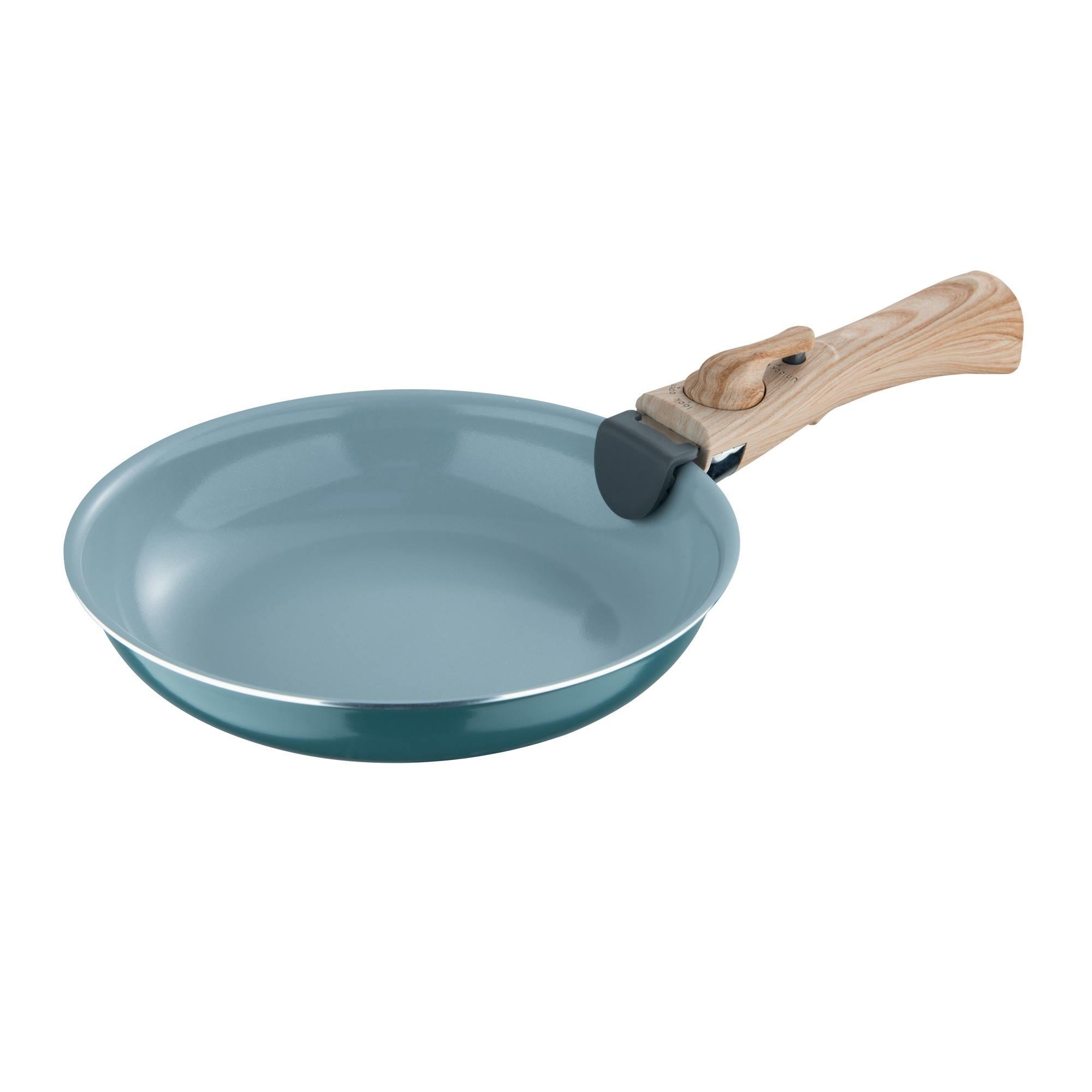 Una sartén verde azulado con mango de madera sobre fondo blanco. El mango tiene un cierre negro y gris.