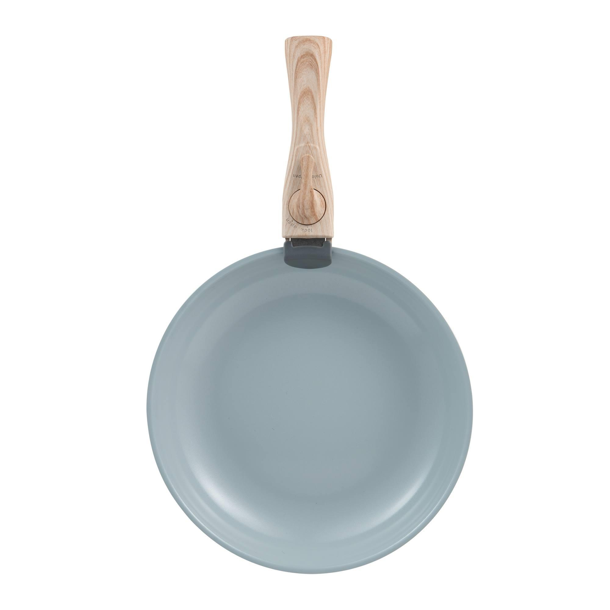 Una sartén azul claro con mango de madera centrada sobre fondo blanco.