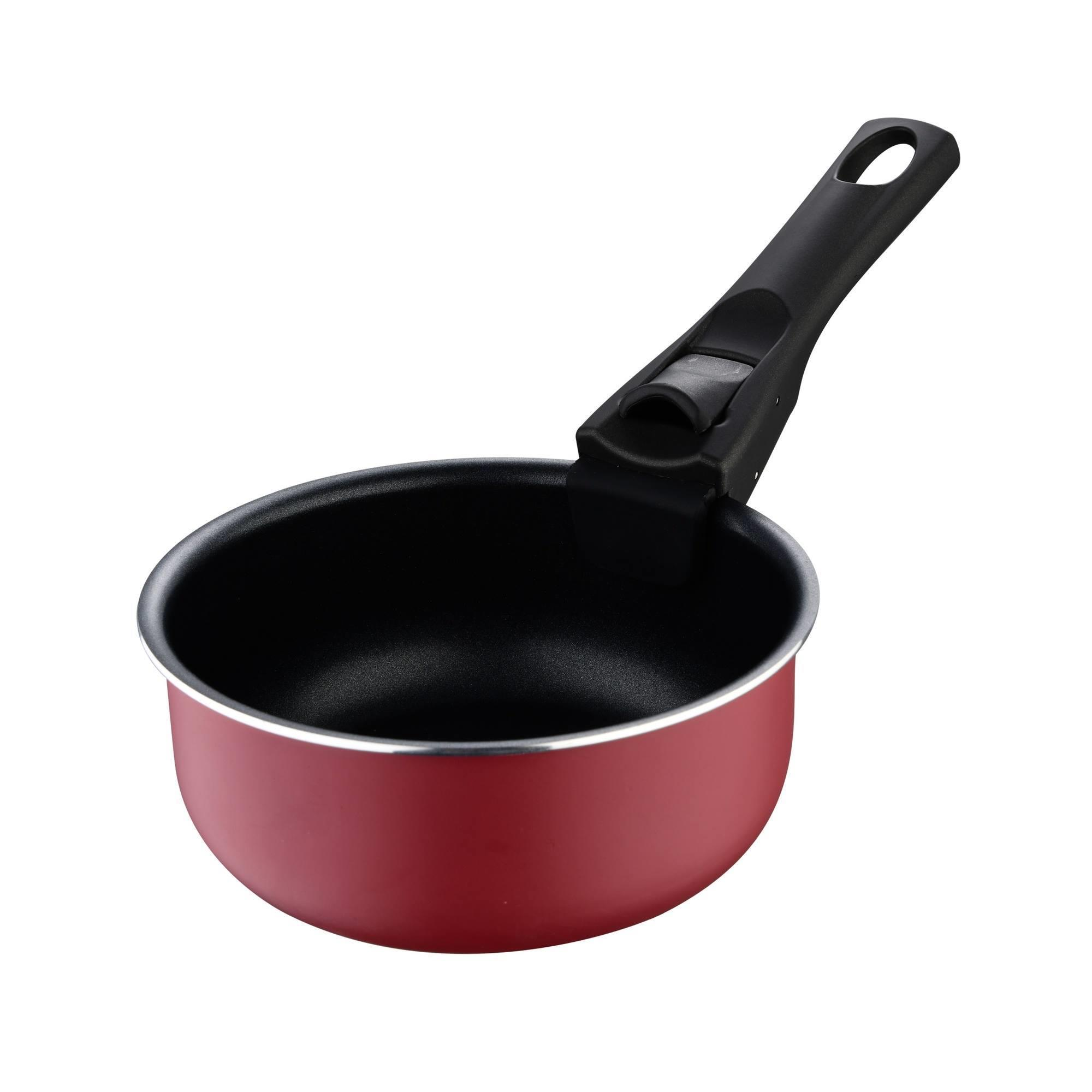 Una cacerola roja con mango negro. El interior es negro. El fondo es blanco.
