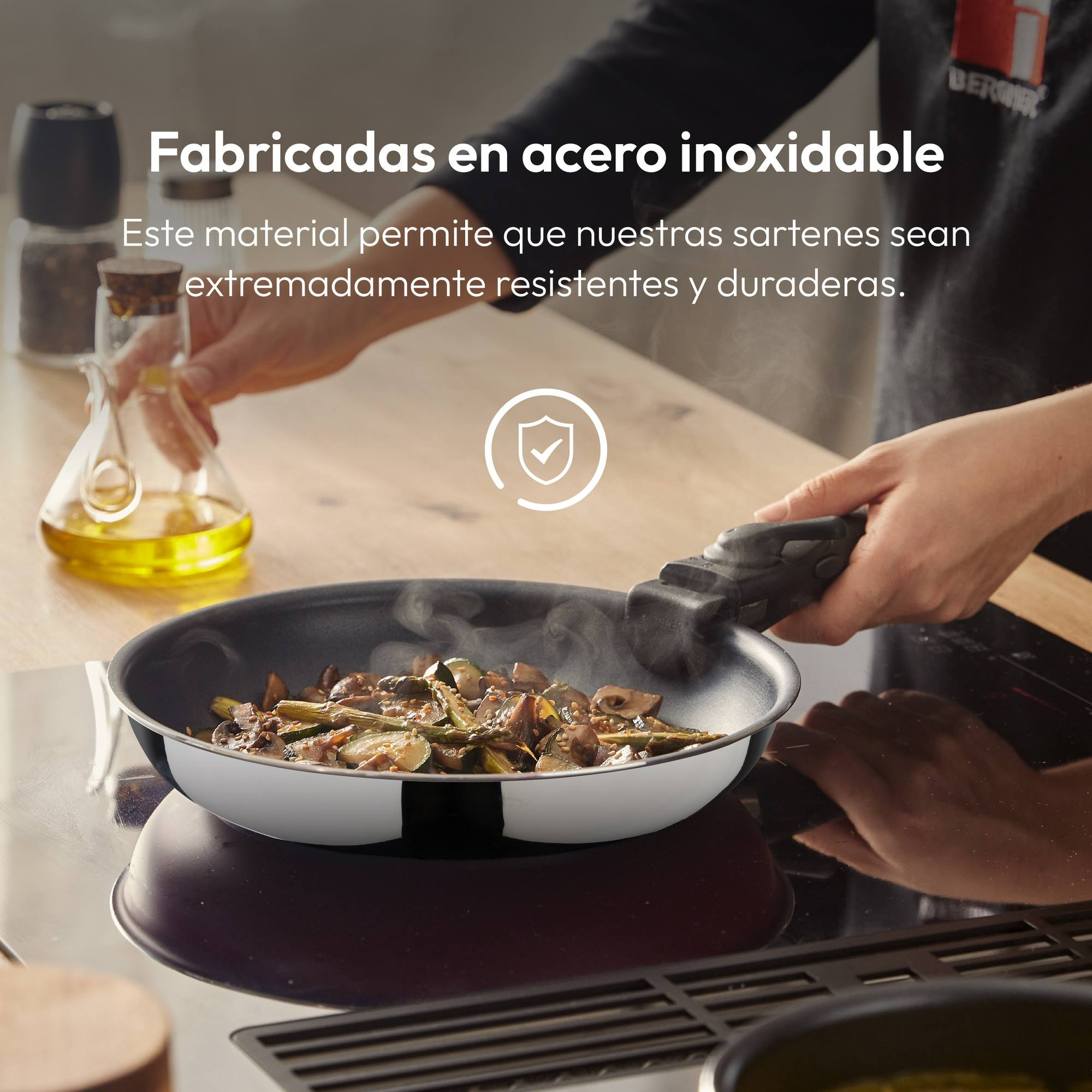 Una sartén con verduras se sostiene sobre una estufa. La sartén tiene un mango negro. Se ve la mano de una persona.