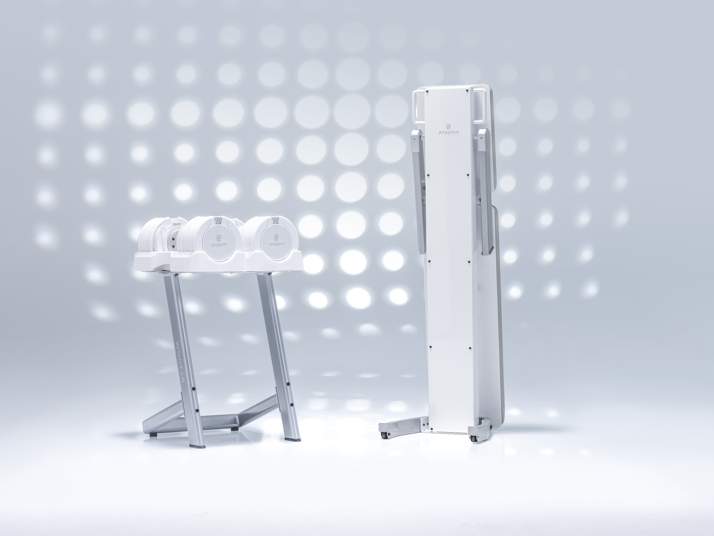 Ensemble d'appareils de fitness blancs. Haltères sur support et une grande machine pliable sur fond clair.