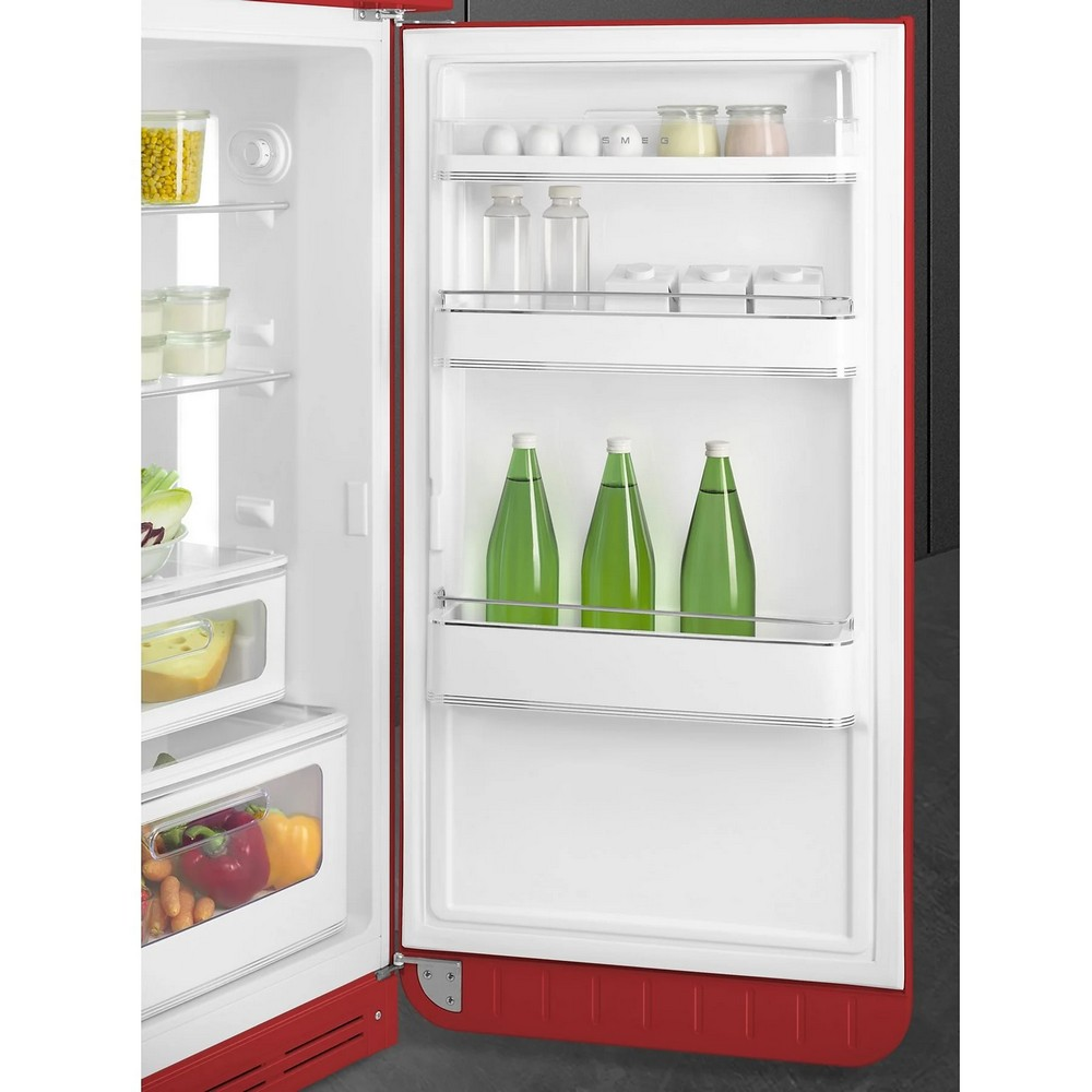 Un refrigerador rojo abierto con estantes llenos de alimentos como huevos, frascos y botellas verdes.