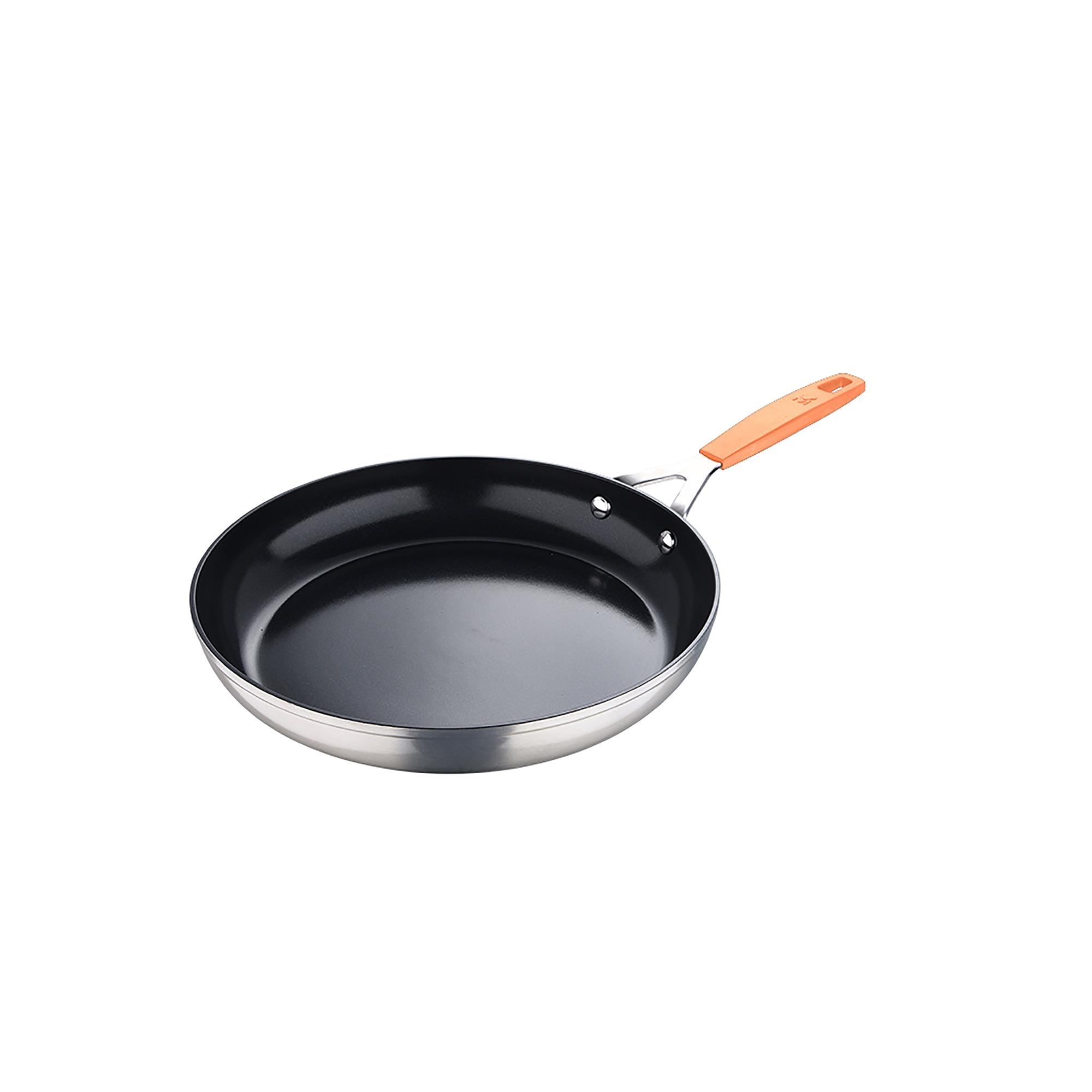 Una sartén antiadherente con interior negro, borde plateado y mango naranja, aislada sobre blanco.