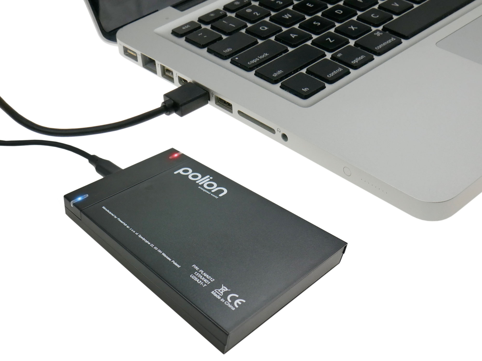 Czarny zewnętrzny dysk twardy jest podłączony do srebrnego laptopa. Dysk ma czerwoną lampkę, a klawiatura laptopa jest widoczna.