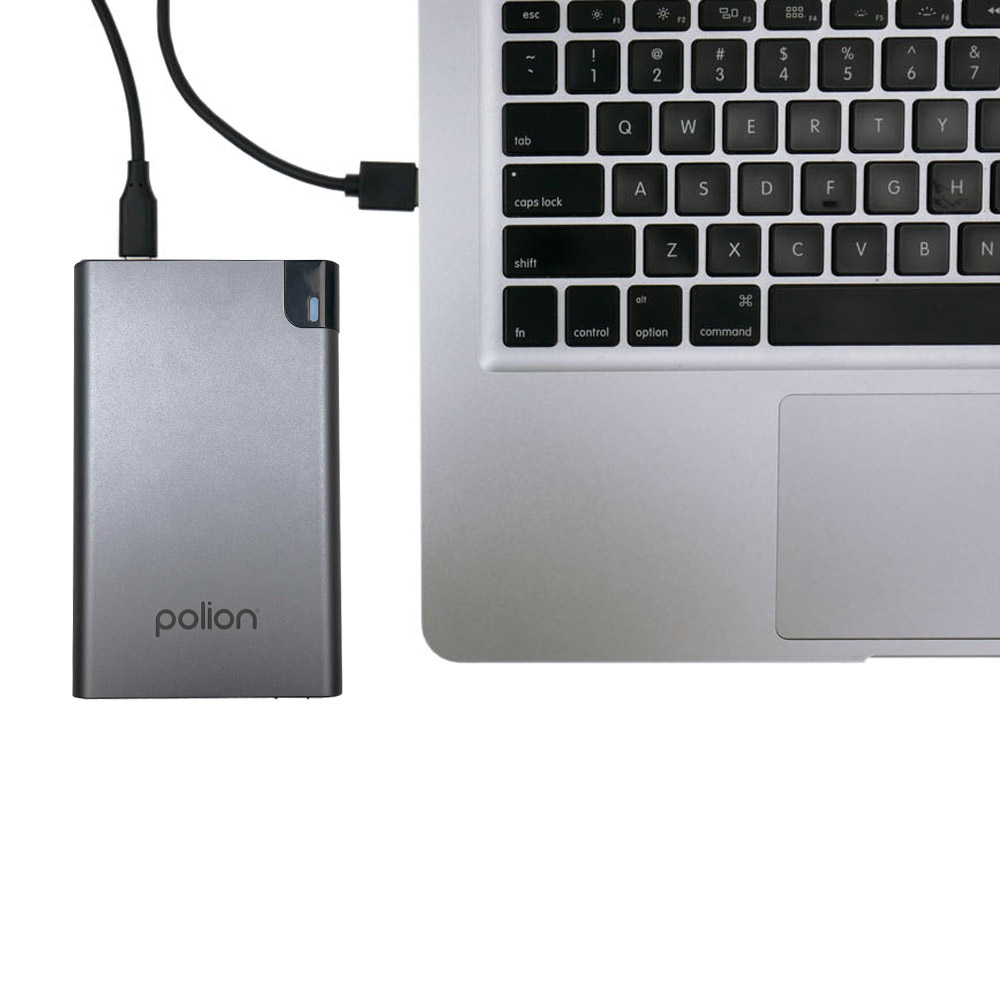 Srebrny zewnętrzny dysk twardy, logo 'polion', podłączony do laptopa przez USB. Widoczna klawiatura laptopa.