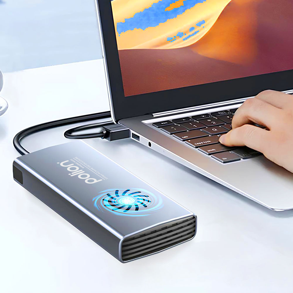 Srebrny zewnętrzny dysk twardy jest podłączony do laptopa. Ręka pisze na klawiaturze. Tło ma ciepły kolor.