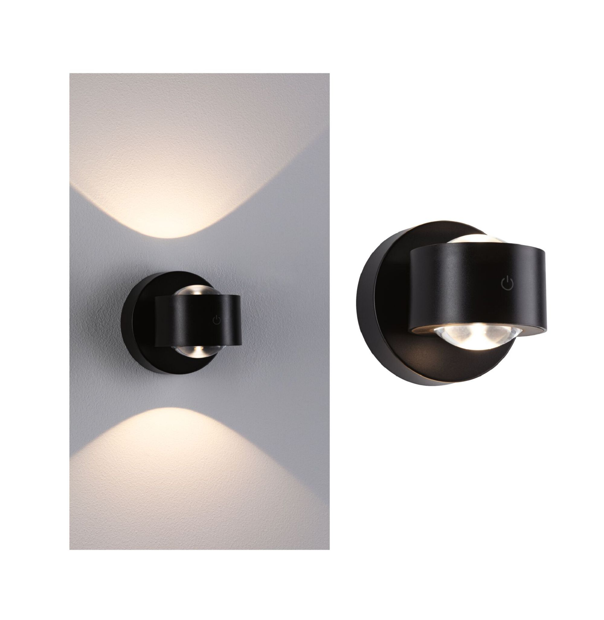 Czarna lampa ścienna. Ma okrągłą podstawę i cylindryczne światło. Światło jest włączone. Białe tło ściany.