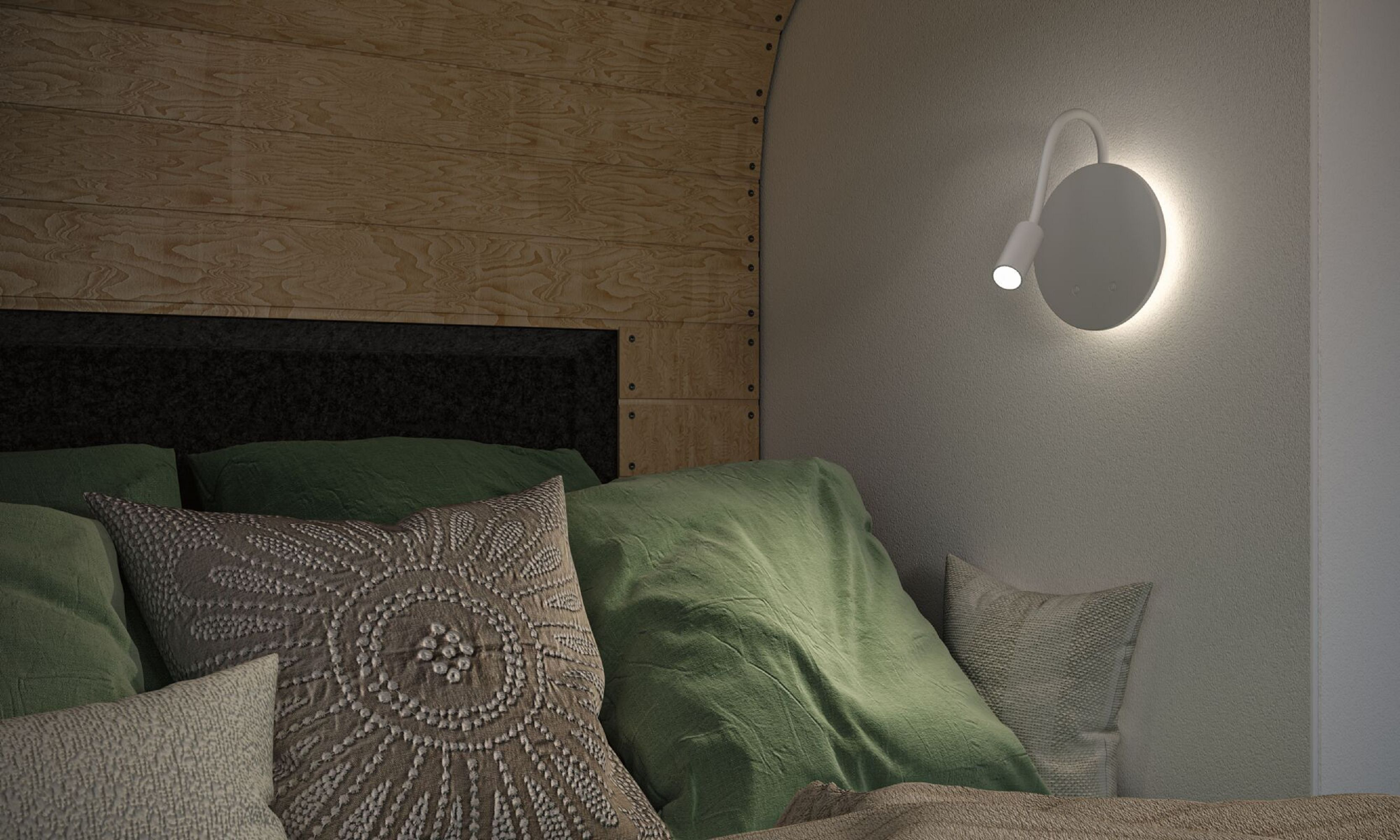 Scena sypialni z poduszkami, zielonym kocem, drewnianym wezgłowiem i białą lampą ścienną z jasnym światłem.