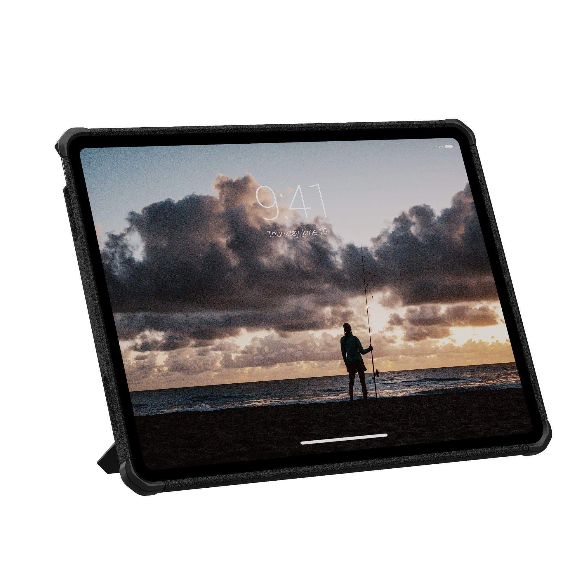 Tablet wyświetlający scenę na plaży z osobą łowiącą ryby. Ciemna ramka, białe tło. Wyświetlany czas: 9:41, czwartek, 16 czerwca.