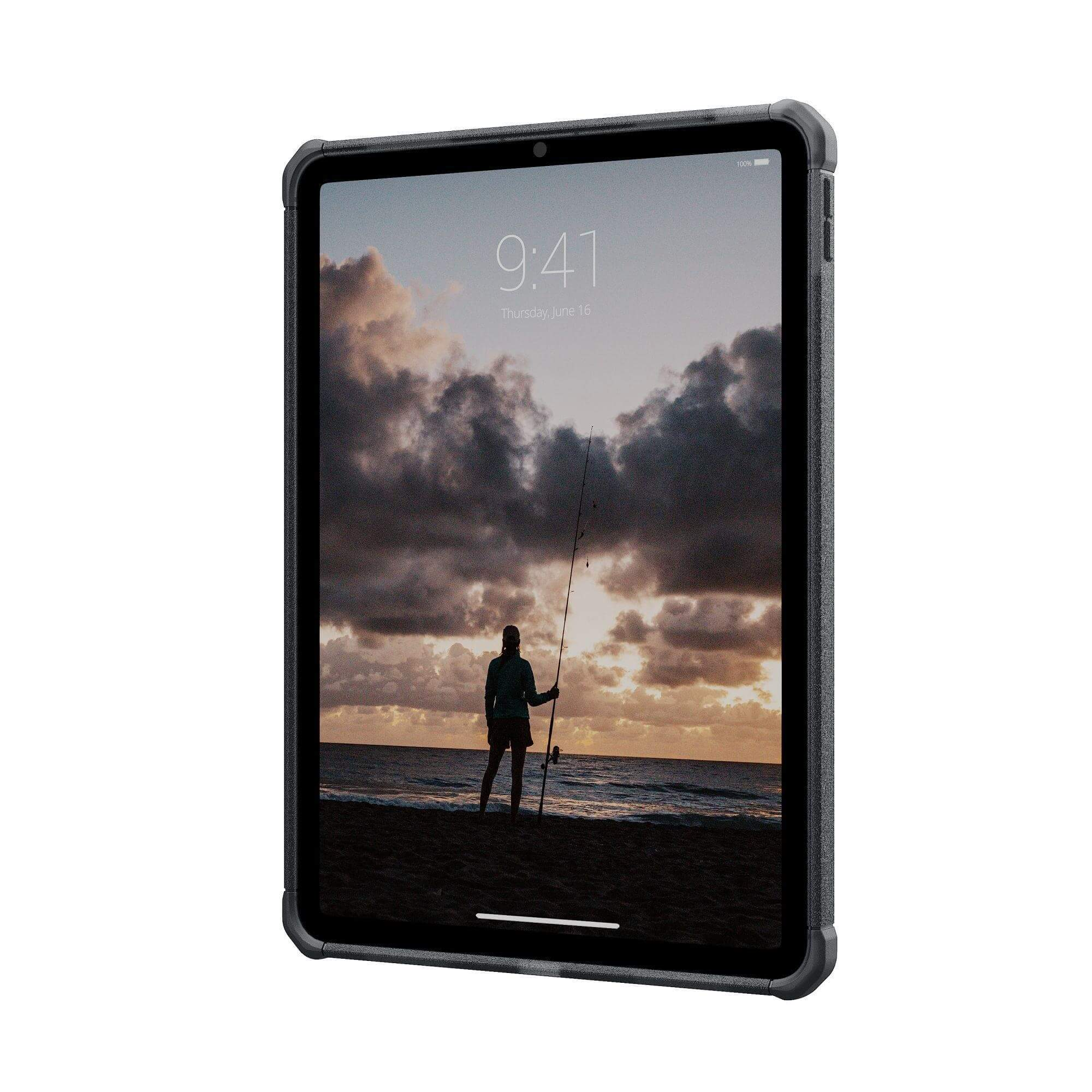 Tablet wyświetlający scenę na plaży z osobą łowiącą ryby o zachodzie słońca. Tablet jest w szarej obudowie.