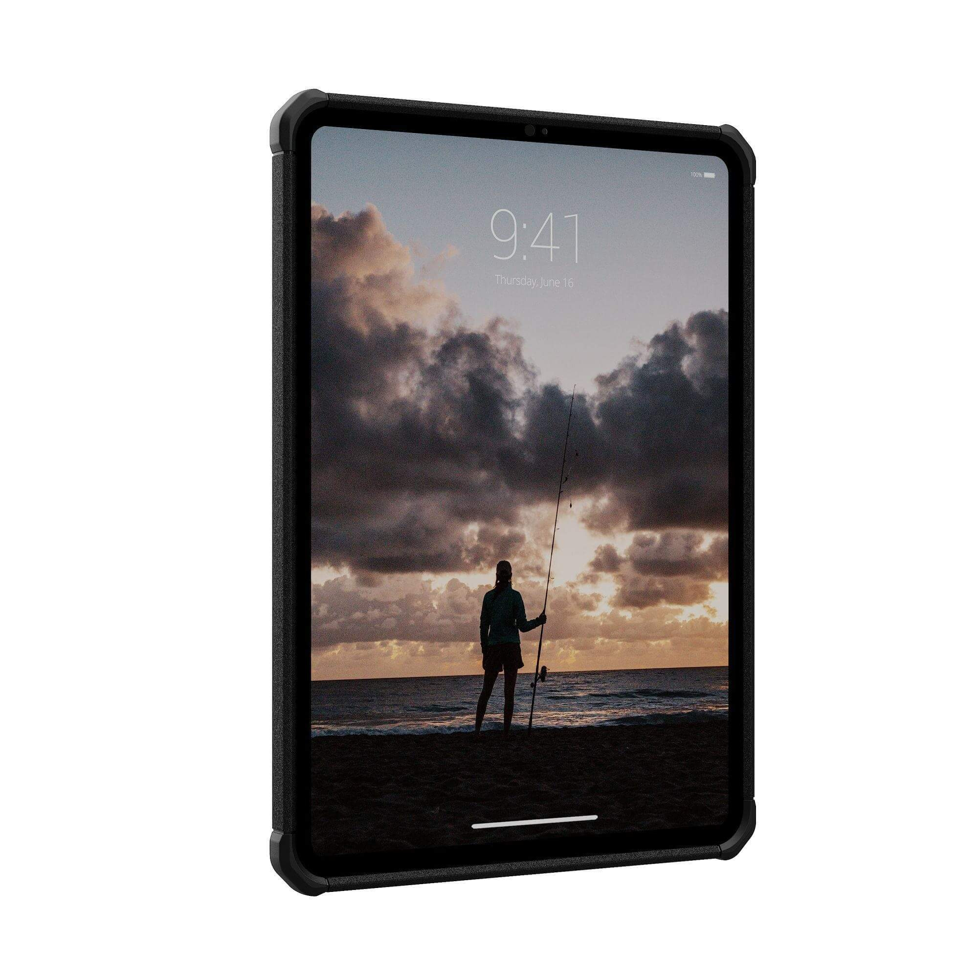 Tablet z widokiem na plażę. Osoba z wędką stoi na brzegu o zachodzie słońca. Ciemna obudowa otacza ekran.
