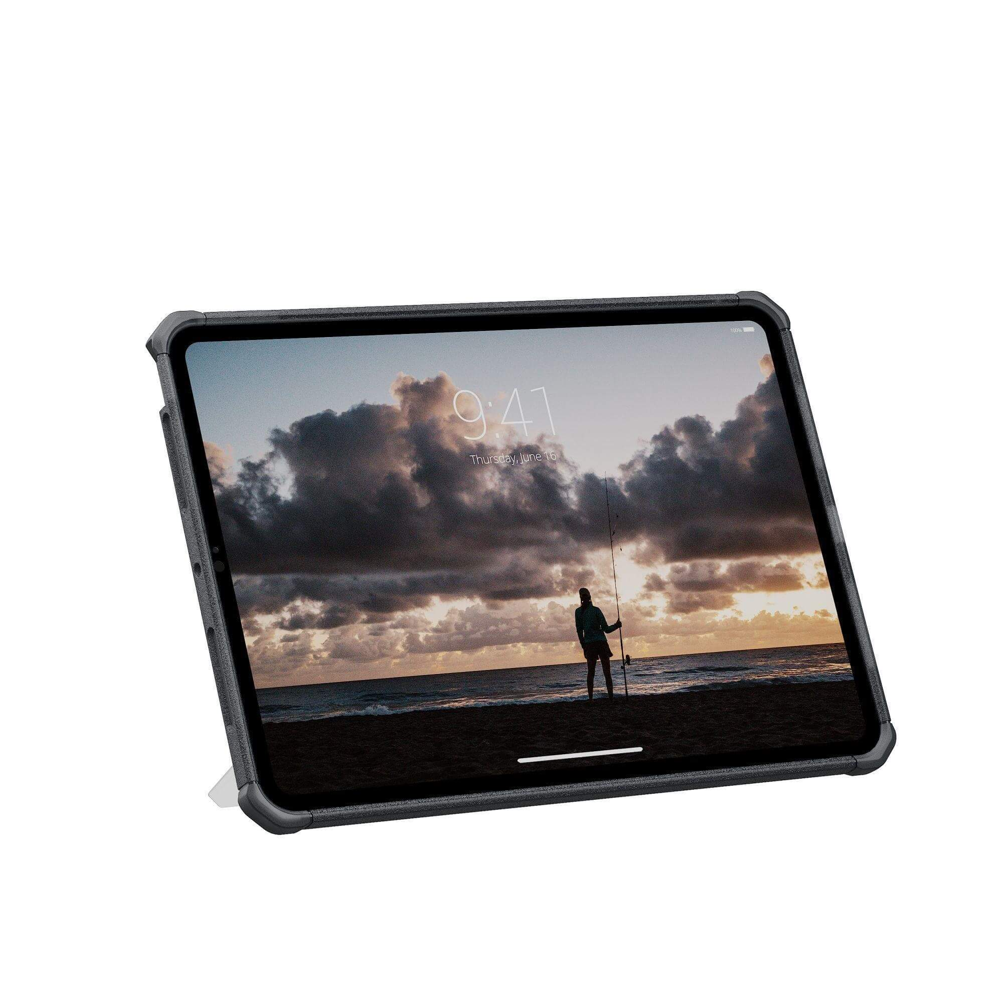 Tablet wyświetlający scenę plażową z wędkującą osobą. Widoczne ciemne chmury i zachód słońca.