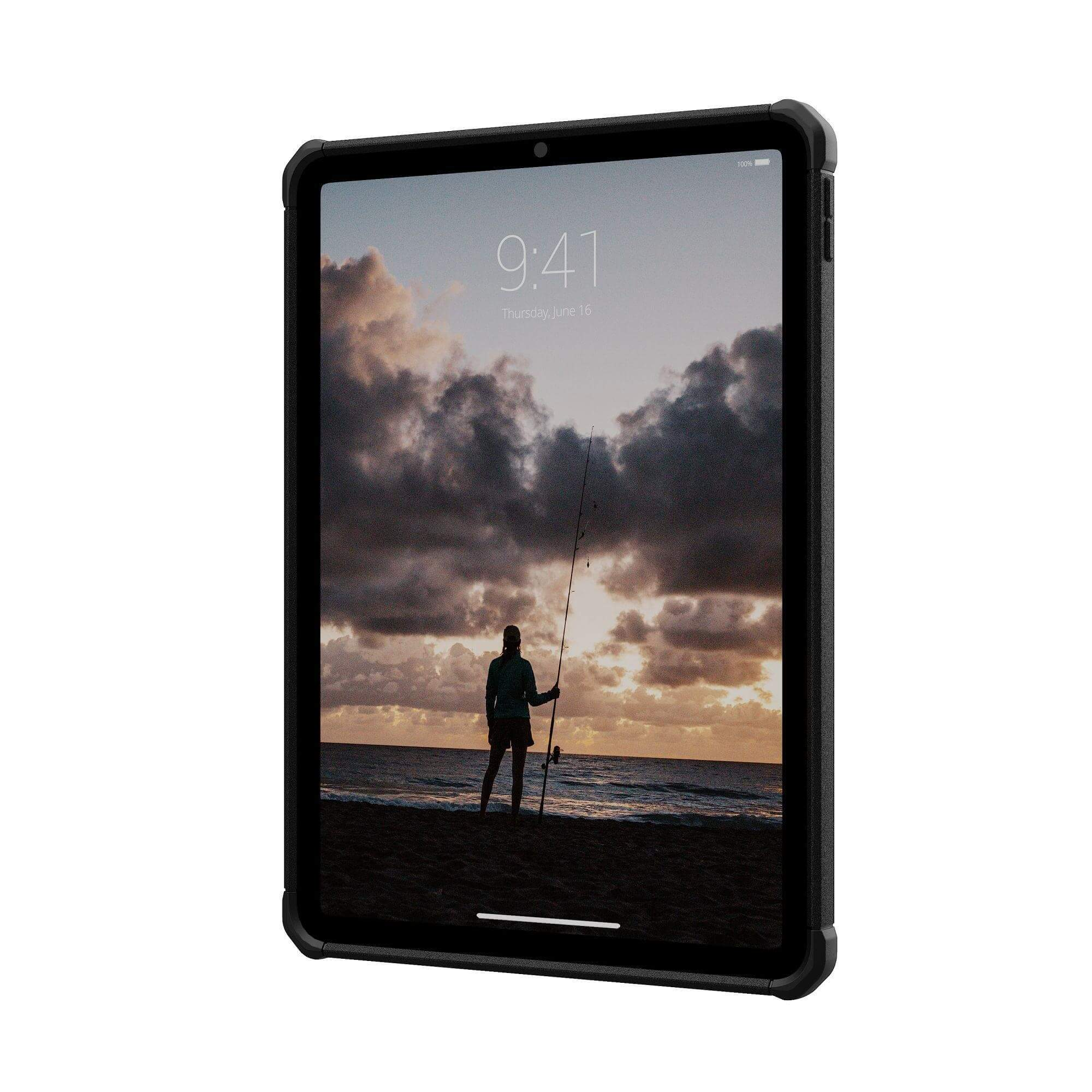 Tablet wyświetlający scenę plażową z osobą łowiącą ryby o zachodzie słońca. Tablet jest w czarnym etui.