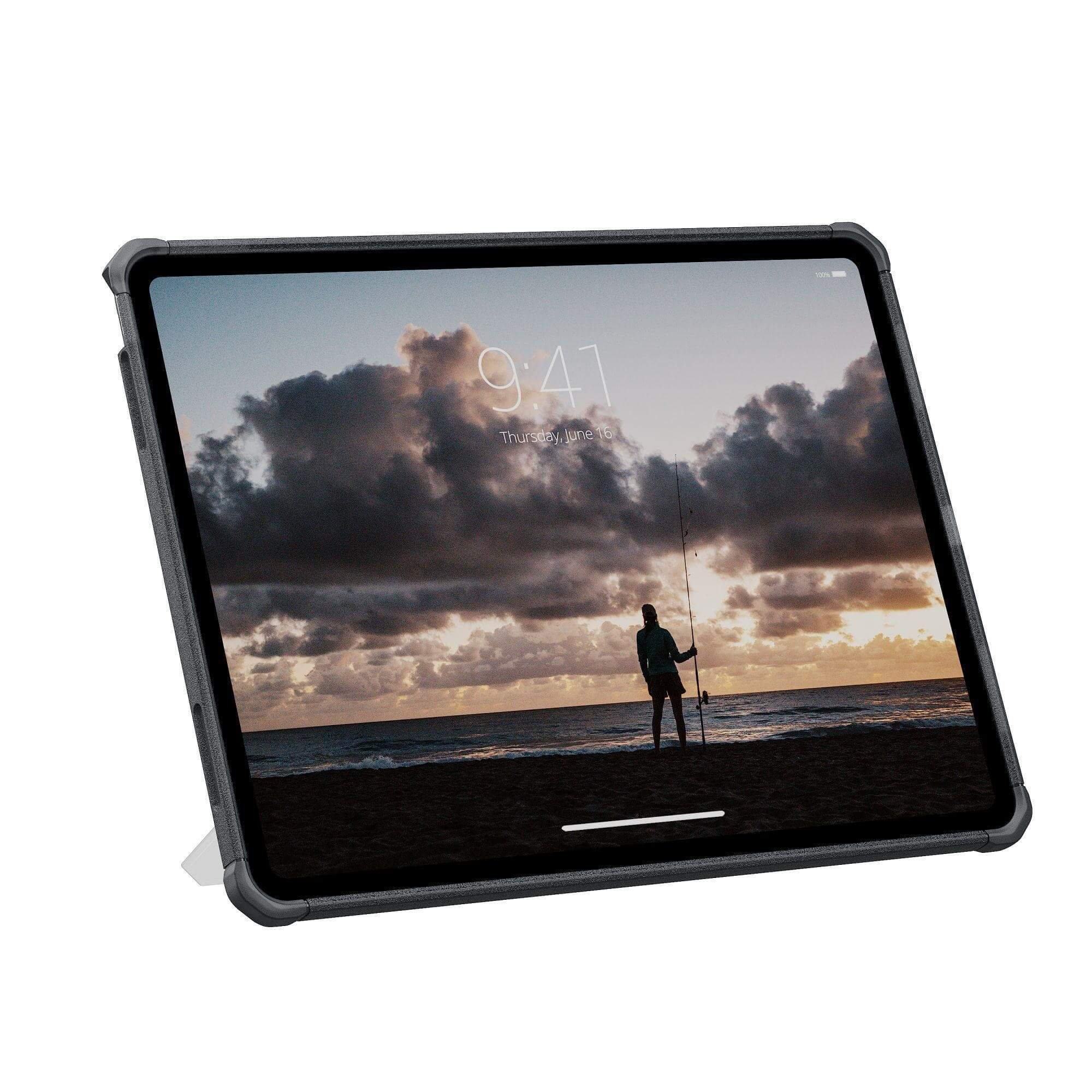Tablet wyświetlający scenę na plaży z osobą łowiącą ryby. Widoczne ciemne chmury, kolory zachodu słońca i godzina 9:41.