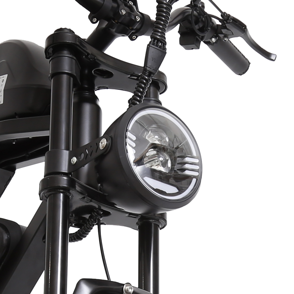 Nahaufnahme eines schwarzen Motorradscheinwerfers. Der Scheinwerfer ist rund und hat ein hellweißes Licht. Lenker und Gabel sind sichtbar.