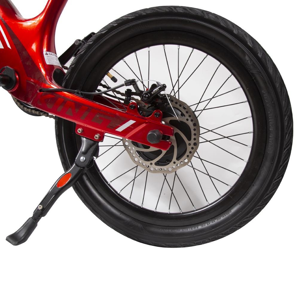 Tylne koło czerwonego roweru elektrycznego. Czarna opona, srebrny hamulec tarczowy i szprychy są widoczne. Stopka jest opuszczona.