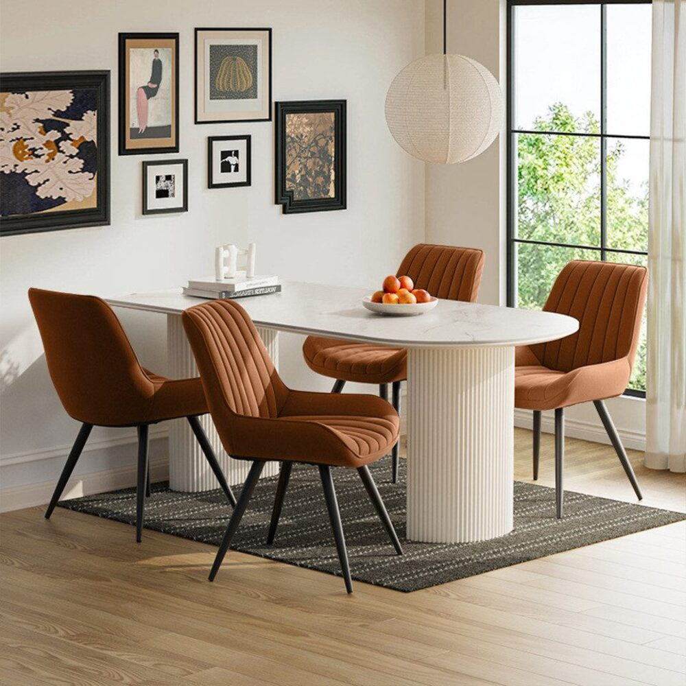 Esszimmer mit weißem Tisch, braunen Stühlen und Kunstwerken an der Wand. Ein Teppich und eine Lampe sind vorhanden. Fenster rechts.