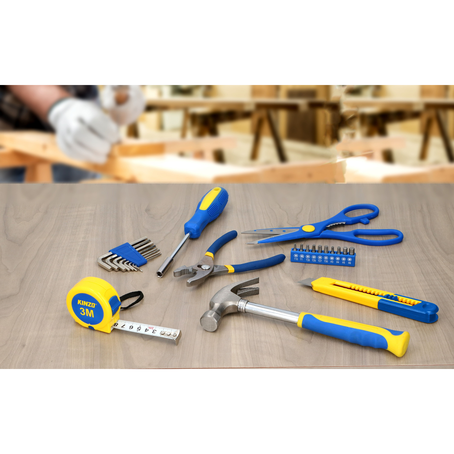 Gereedschap op houten oppervlak: meetlint, hamer, tang, schroevendraaier en schaar.