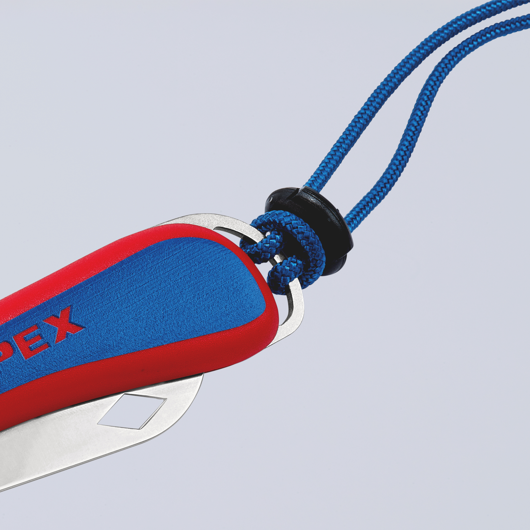 Una multiherramienta con mango rojo y azul, sujeta a un cordón azul. El fondo es gris degradado.