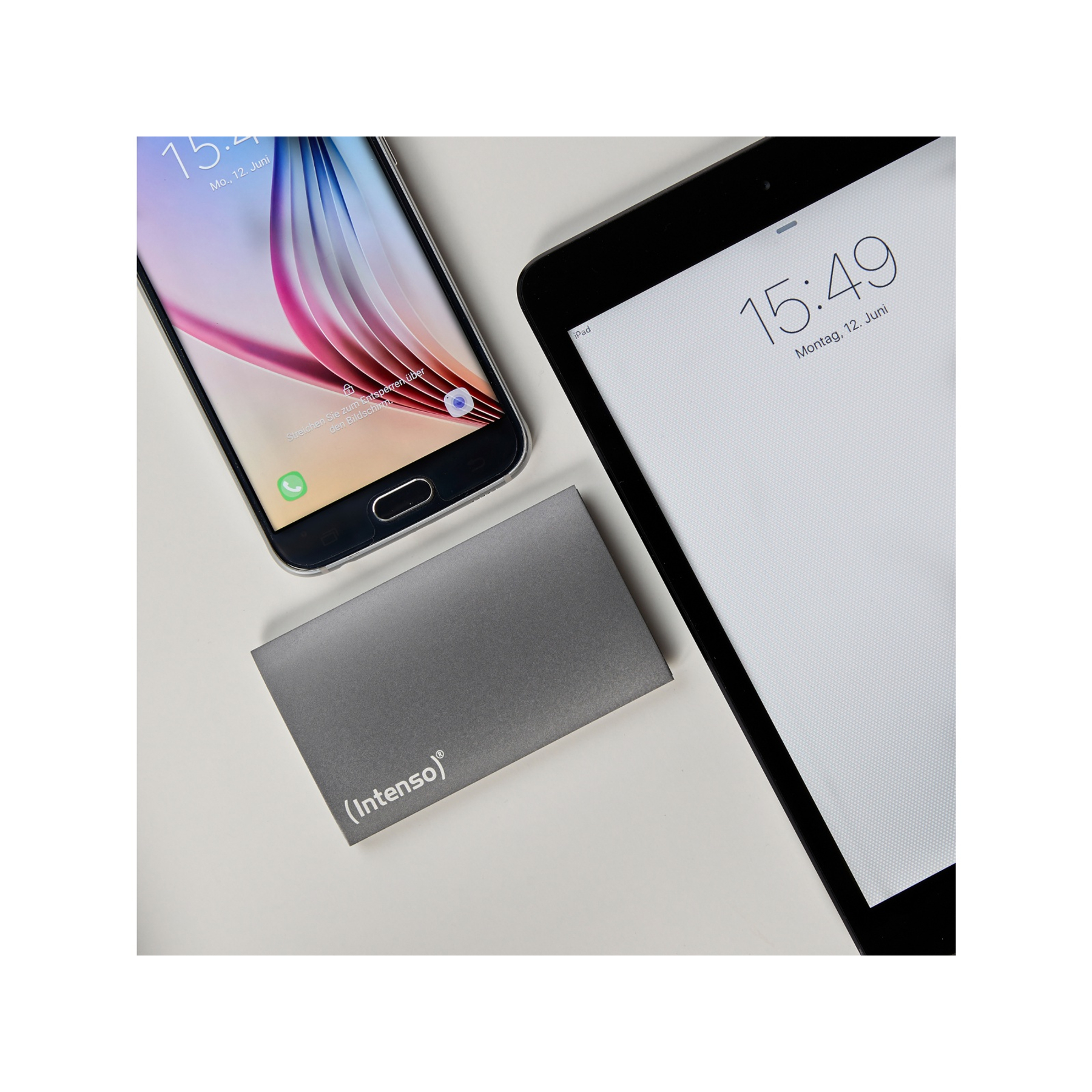 Smartfon, tablet i szary dysk twardy na białej powierzchni. Telefon i tablet wyświetlają godzinę.