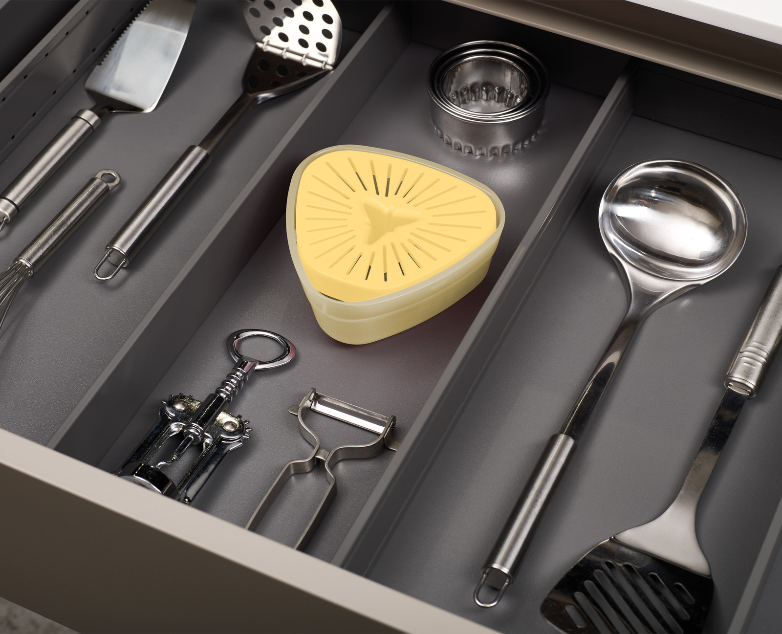 Un cassetto con utensili da cucina. Include uno spremiagrumi, un cavatappi, un pelapatate, una spatola, un mestolo e altri strumenti.