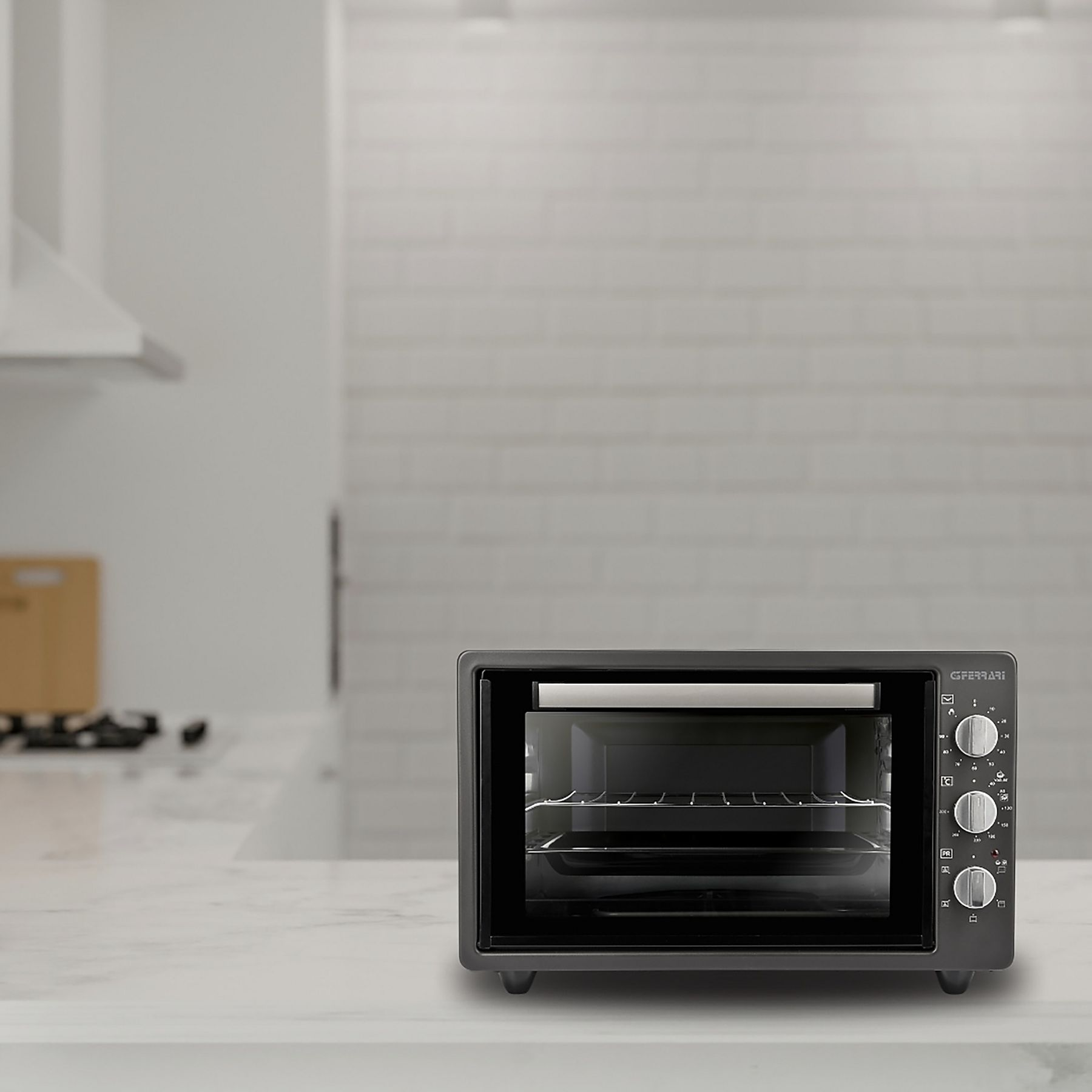 Un forno grigio scuro su un piano di lavoro bianco. Porta a vetro e manopole. Ambiente cucina.