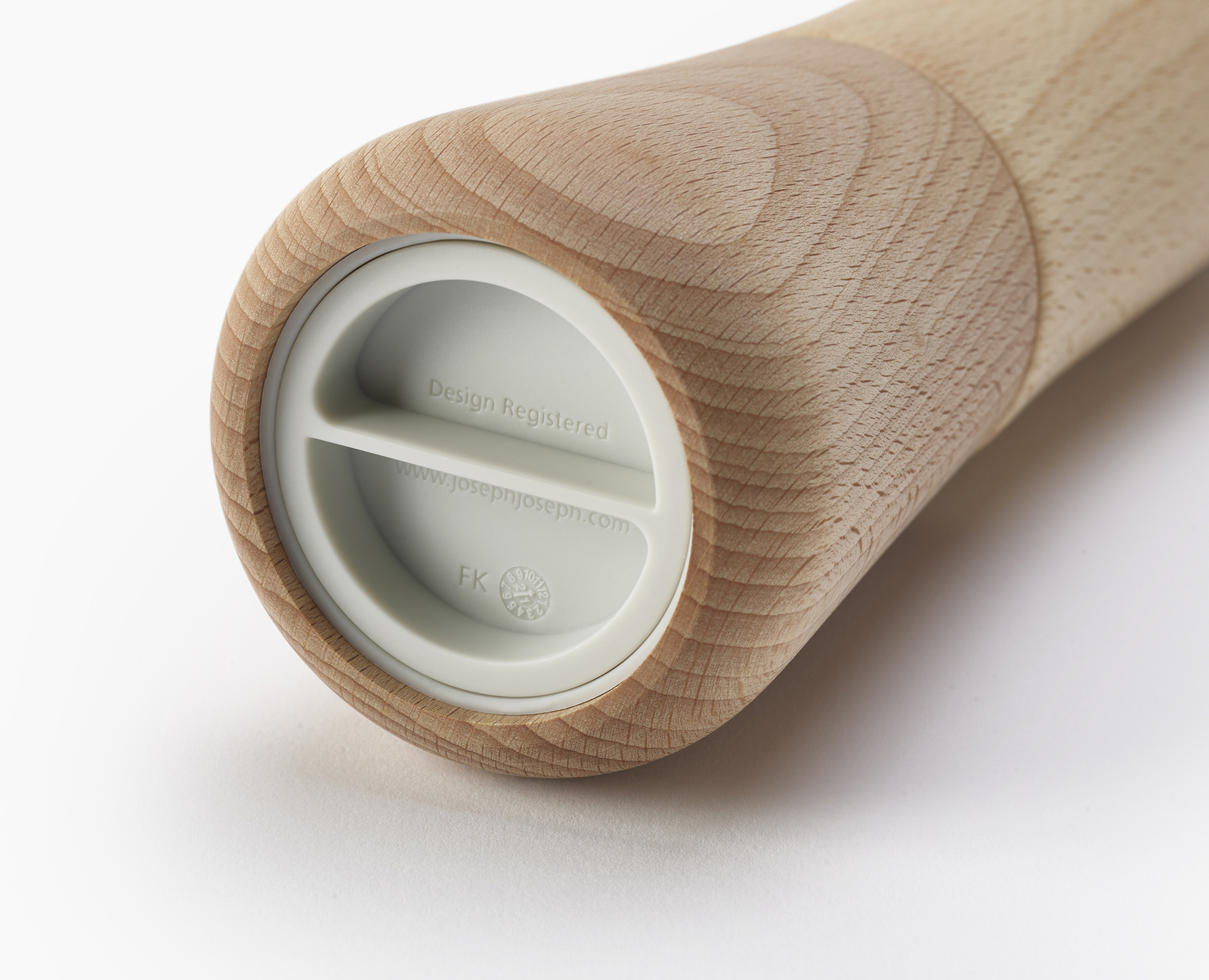 Molinillo de pimienta de madera, primer plano. Inserto blanco con texto: Design Registered, www.josephjoseph.com. Textura de grano de madera clara.
