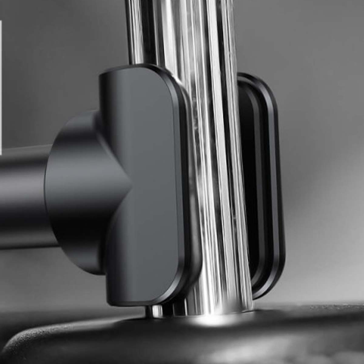 Zbliżenie czarnego uchwytu na telefon przymocowanego do srebrnego metalowego słupka. Uchwyt ma zaokrąglone krawędzie.