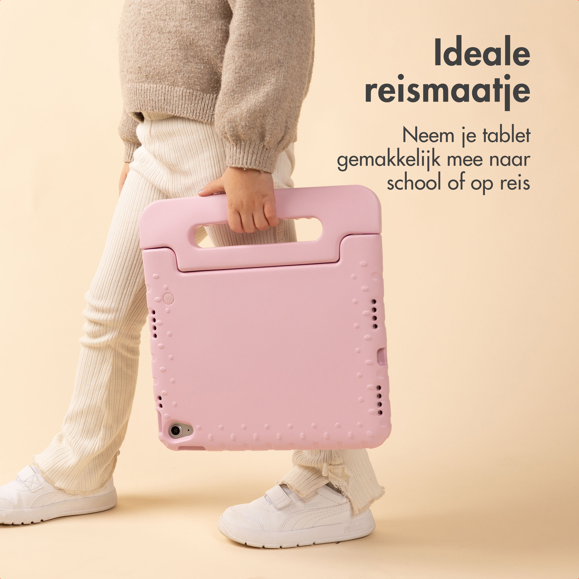 Een kind houdt een roze tablethoes vast. Het kind draagt een beige trui, witte broek en witte schoenen.