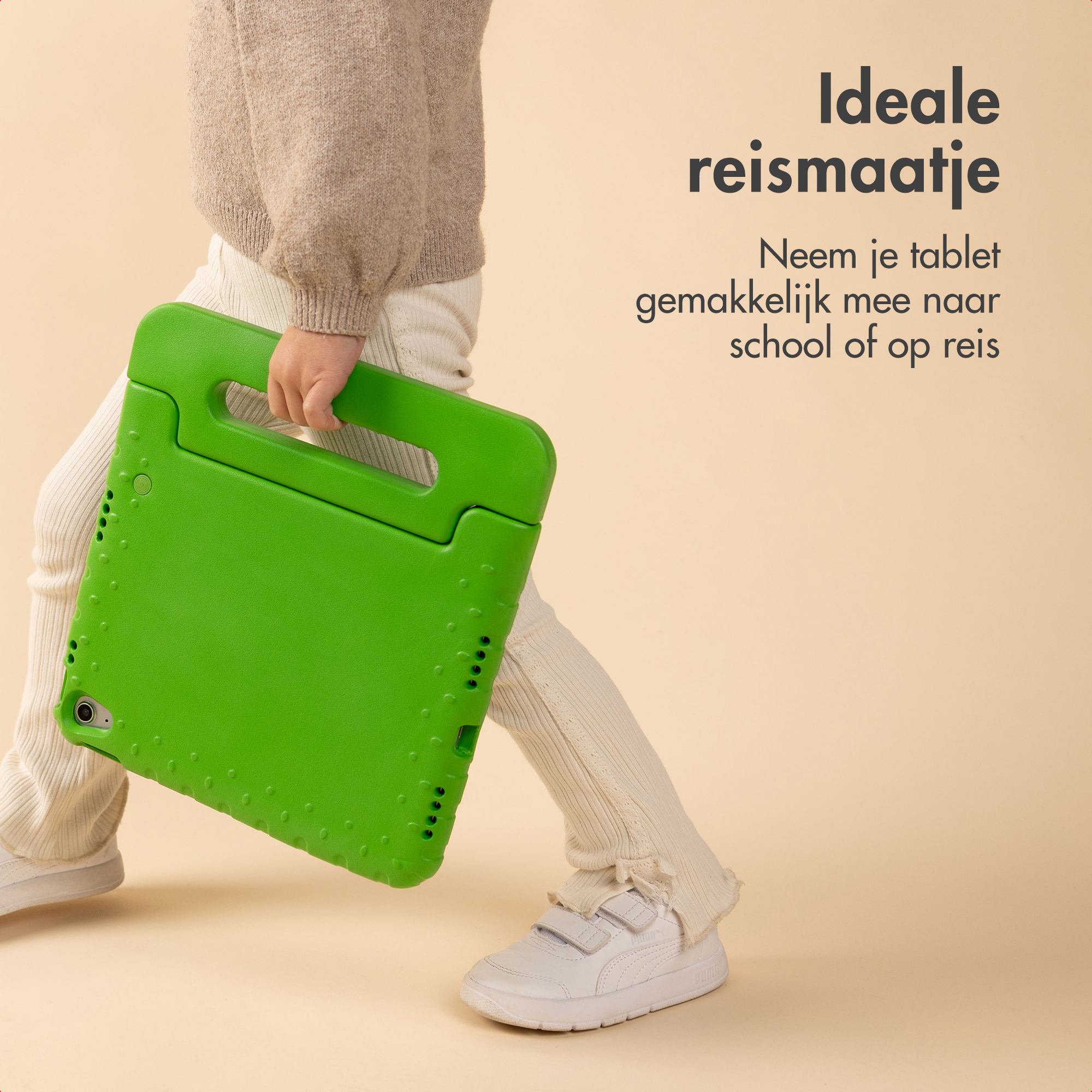 Een kind houdt een groene tablethoes vast. Het kind draagt een beige trui, witte broek en witte schoenen, tegen een beige achtergrond.