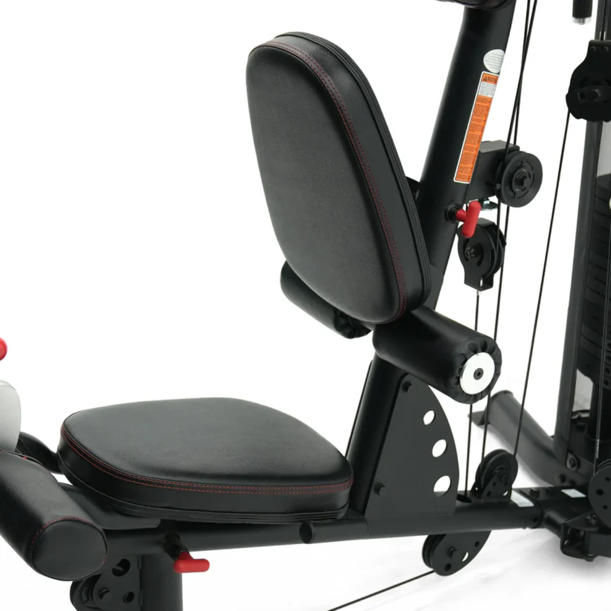 Een close-up van een zwarte fitnessmachine. Het heeft een zitting, rugleuning en armleuningen met rode stiksels. Kabels en katrollen zijn zichtbaar.
