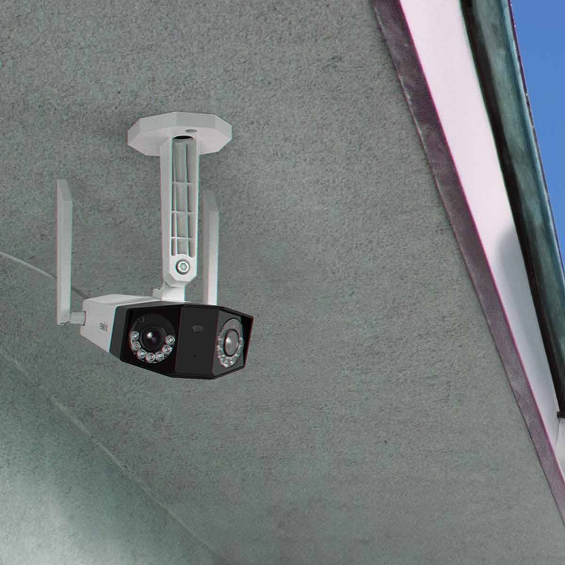 Biało-czarna kamera bezpieczeństwa jest zamontowana na szarym suficie. Ma dwa obiektywy i anteny.