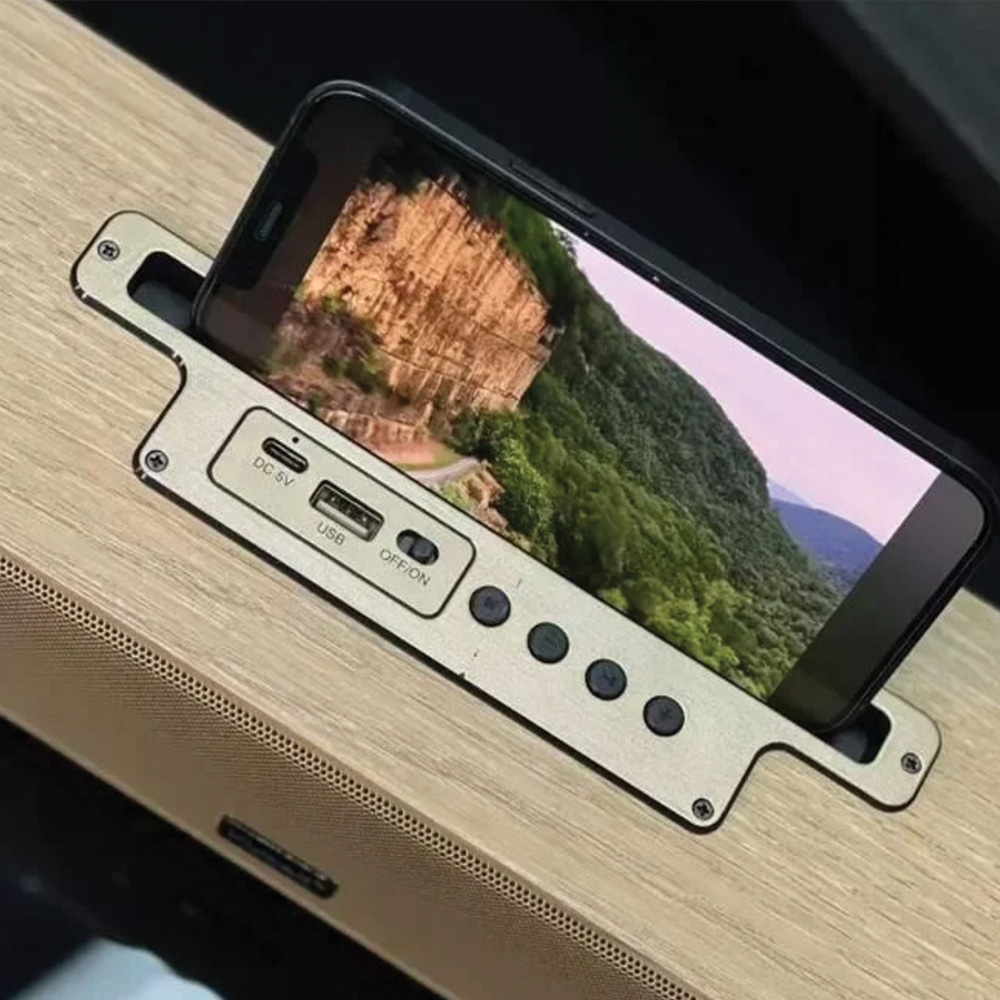 Bir dağ manzarasını gösteren bir telefon hoparlör yuvasında. Yuvanın düğmeleri ve bağlantı noktaları var. Arka plan ahşap bir yüzey.