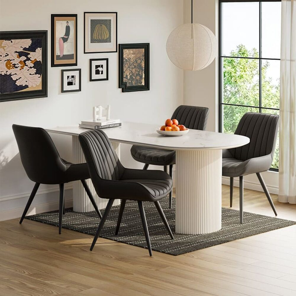 Esszimmer mit weißem ovalem Tisch, schwarzen Stühlen, Kunstwerken an der Wand und einem Teppich. Orangen liegen auf dem Tisch.