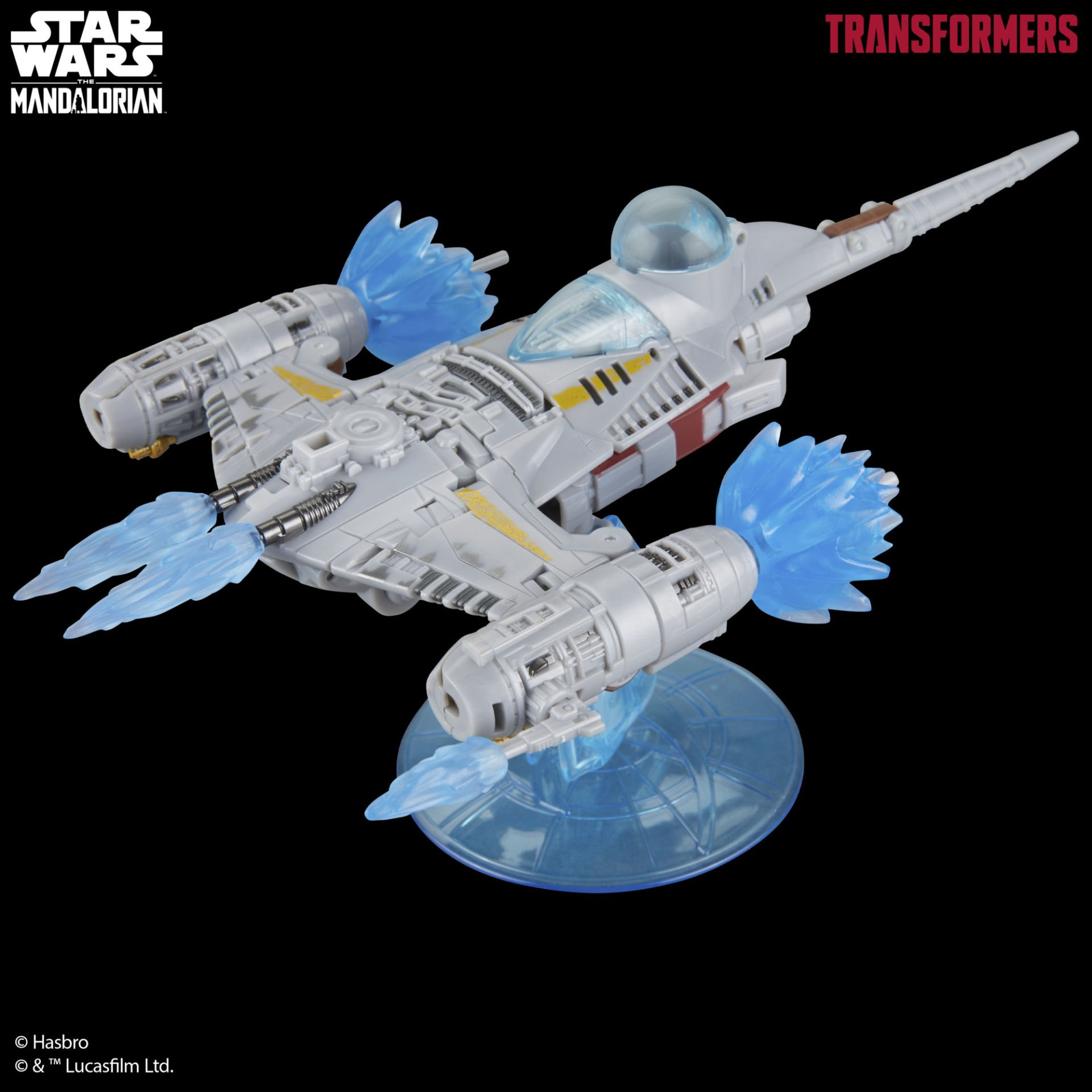 Siyah zemin önünde, mavi enerji patlamaları ve şeffaf bir standı olan gri bir Star Wars Transformers gemisi.