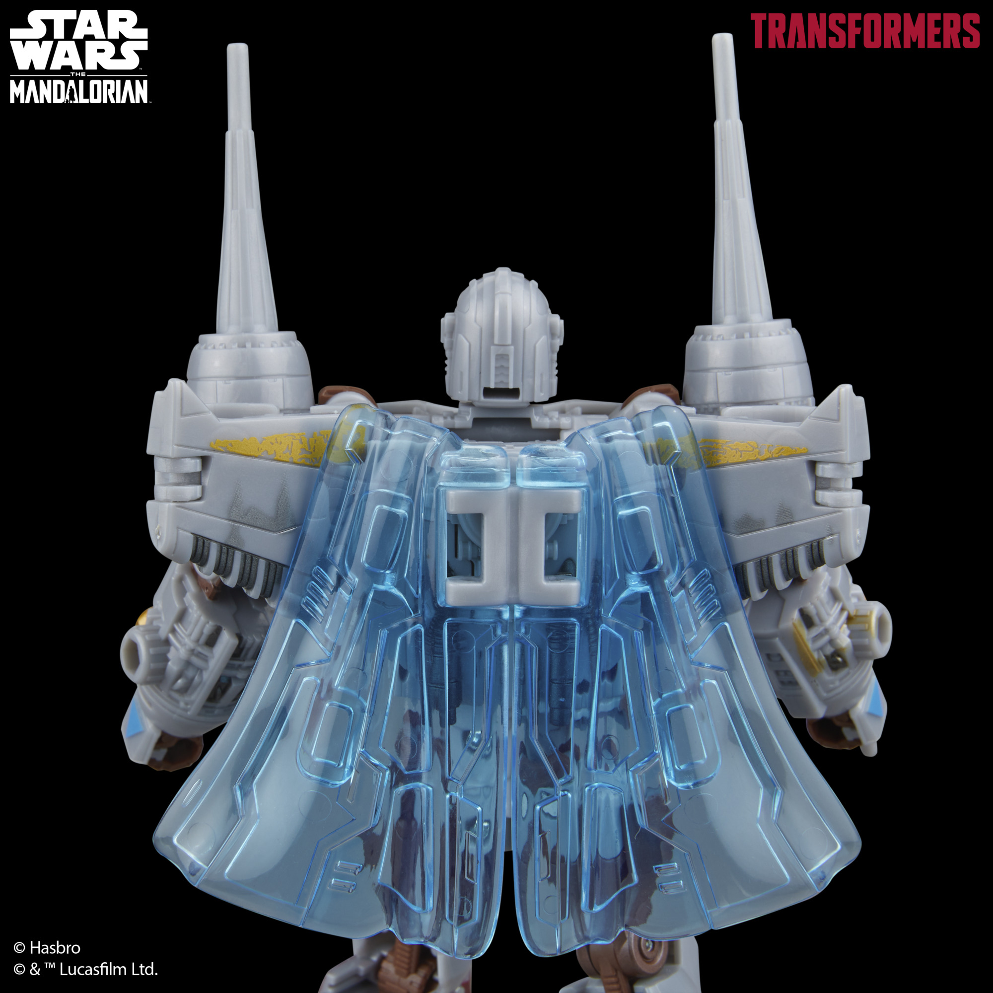 Siyah zemin üzerinde pelerinli gri ve mavi bir Transformer oyuncağı. Star Wars ve Transformers logoları görünür durumda.