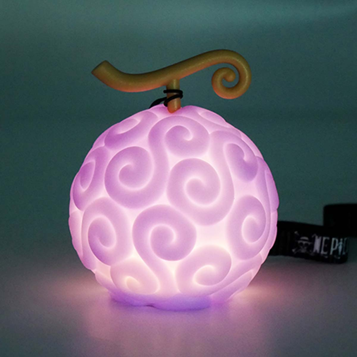 Un oggetto sferico viola brillante con un design a spirale e uno stelo giallo. Si trova su una superficie, con uno sfondo scuro.