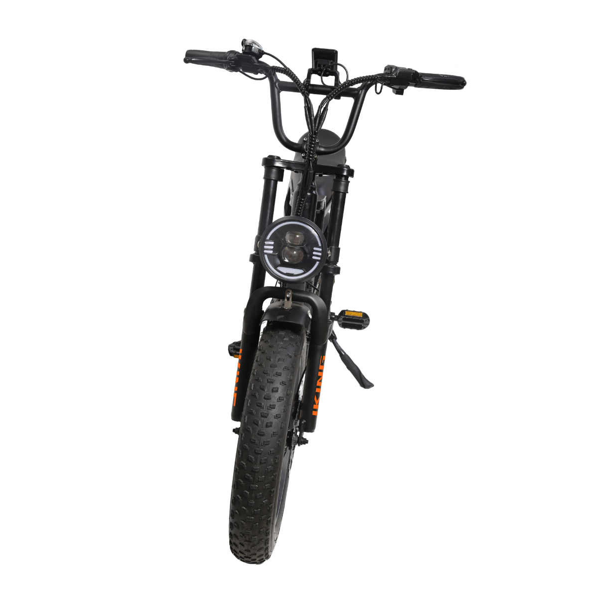 Czarny rower elektryczny. Posiada okrągły reflektor, grube opony i wyświetlacz cyfrowy. Pomarańczowe litery na oponie. Kierownica prosta.