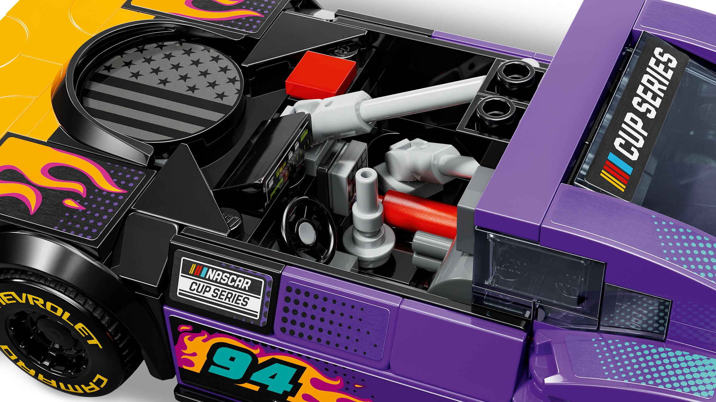 Nahaufnahme eines lila-gelben Rennwagenmodells. Details umfassen Flammen, die Nummer 94 und NASCAR Cup Series-Branding.