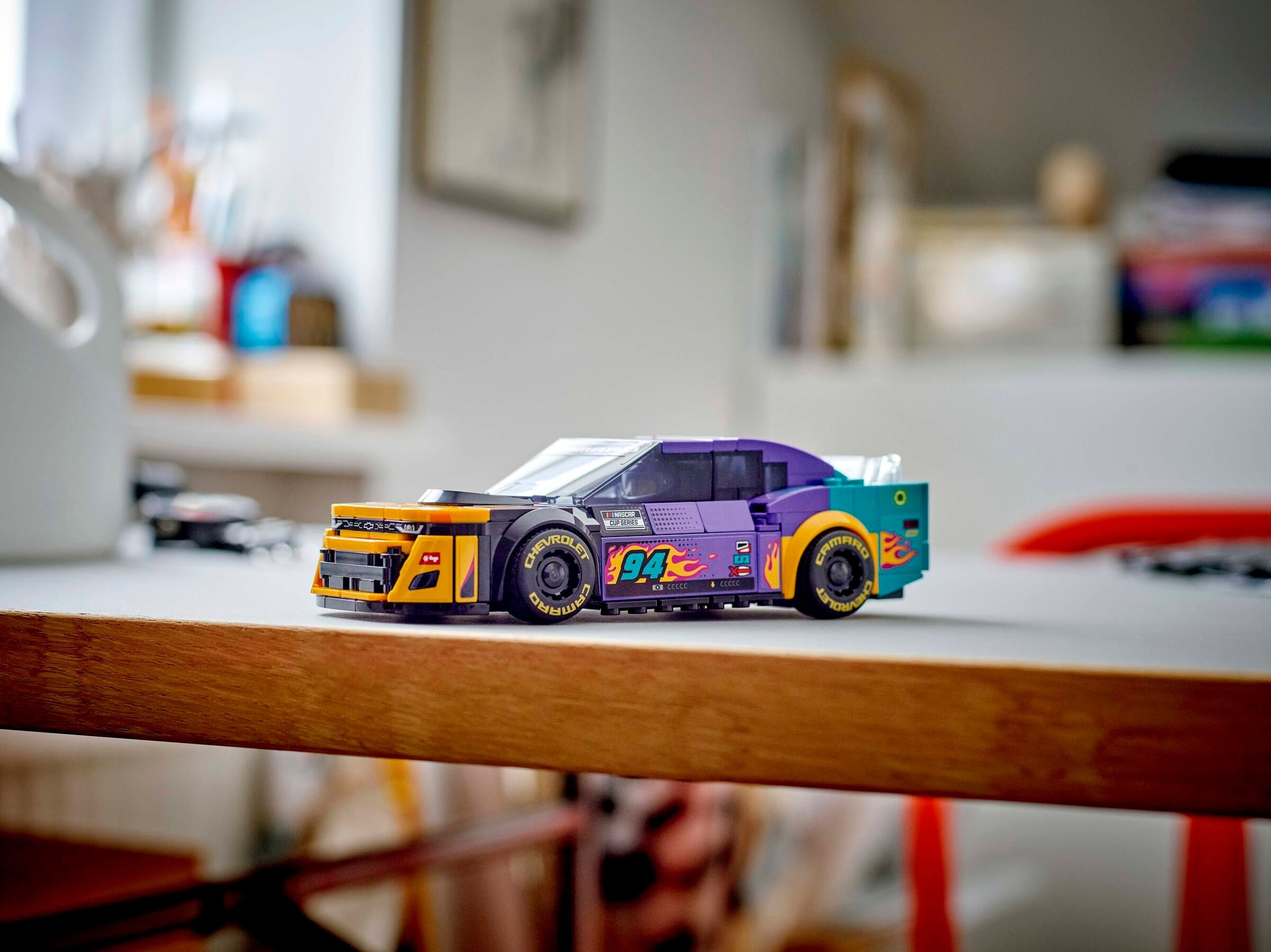 Ein farbenfrohes Lego-Rennauto steht auf einem Tisch. Es hat die Nummer 94. Der Hintergrund ist unscharf.